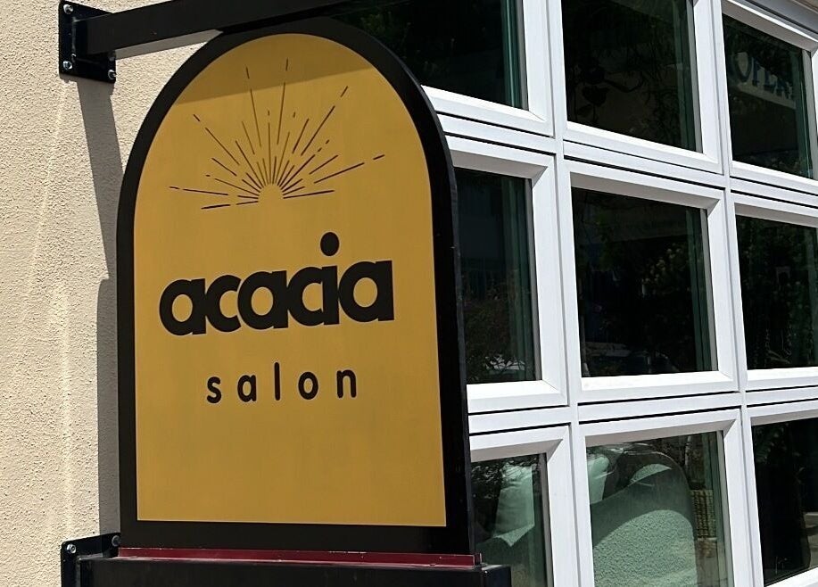 Sign of The Acacia Salon in San Diego, California, US featuring elegant black lettering on a golden background.