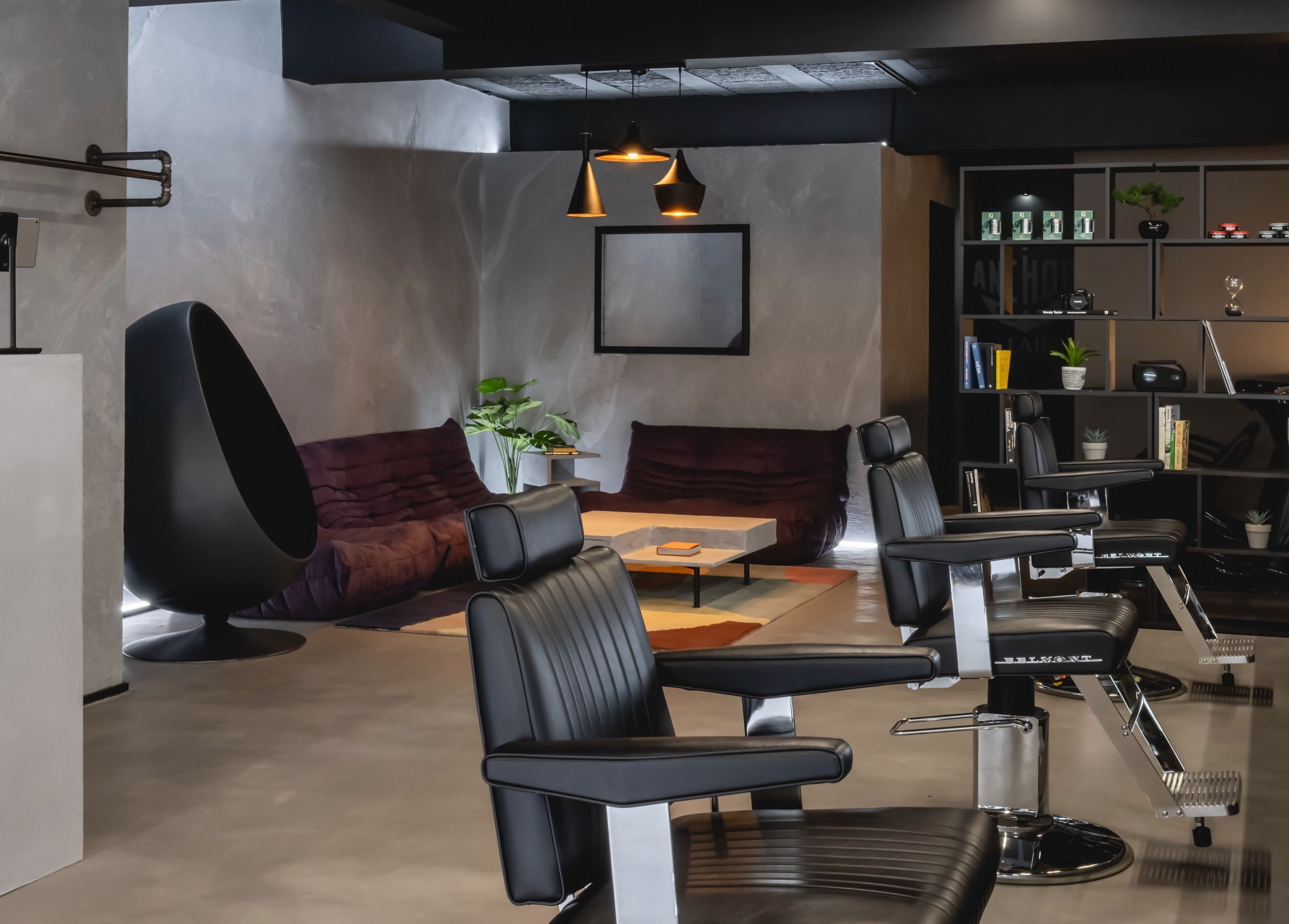 Chic barbershop interior at Anchor Lab, London, England, GB, featuring sleek black chairs and modern decor.
