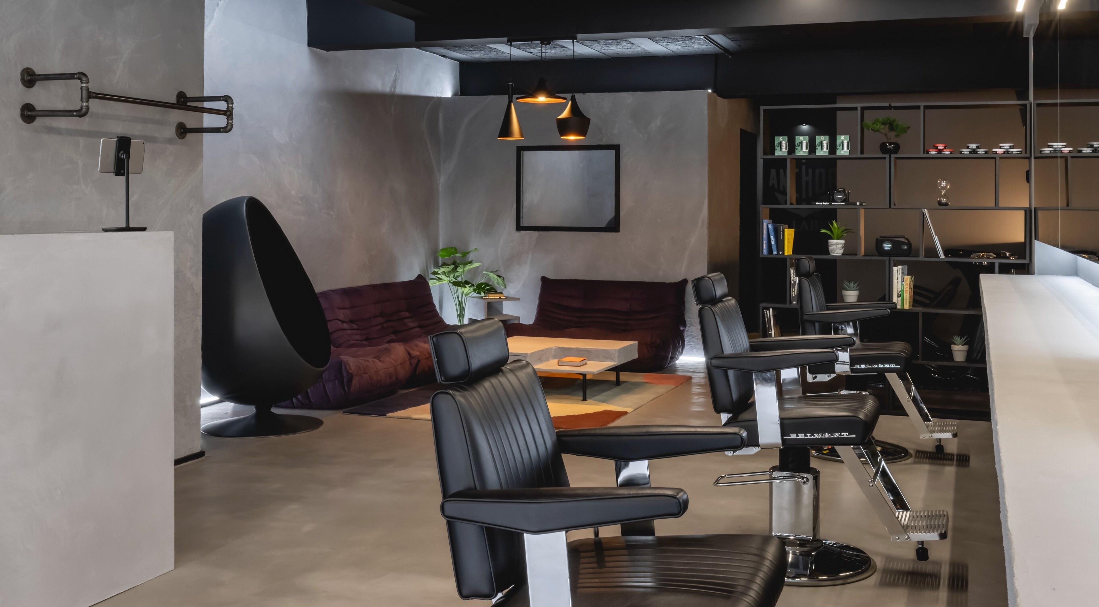 Chic barbershop interior at Anchor Lab, London, England, GB, featuring sleek black chairs and modern decor.