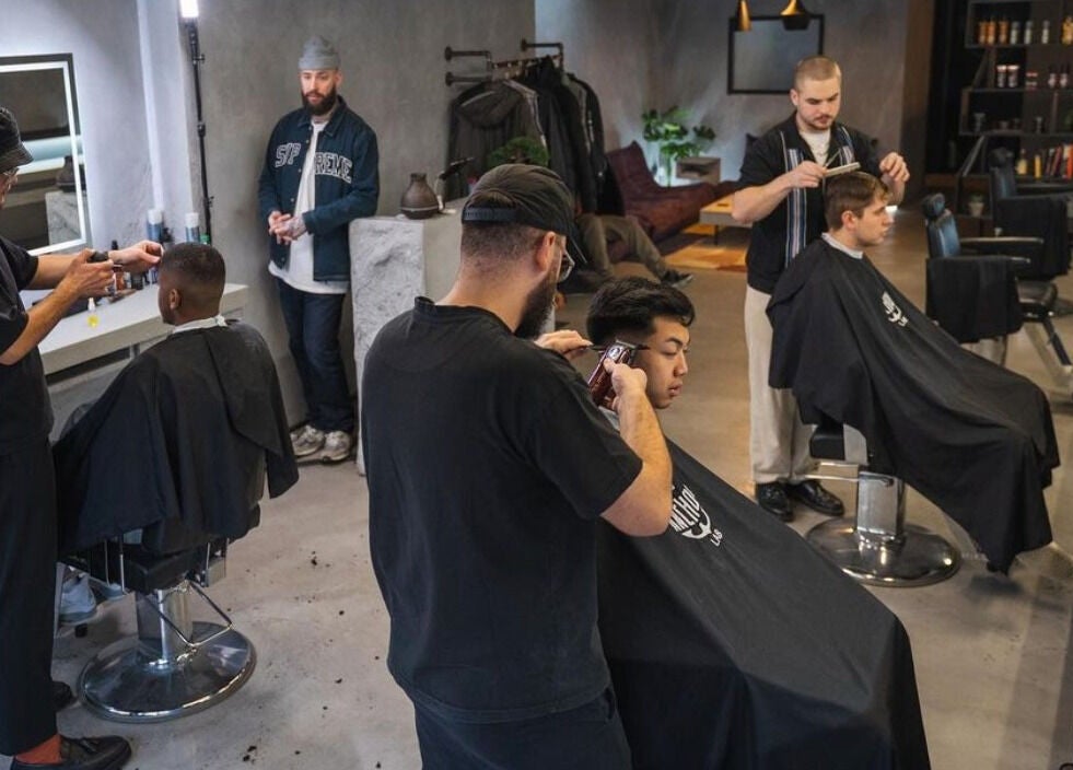 Interior of Anchor Lab, London, England, GB, featuring barbers styling clients in a modern salon setting.