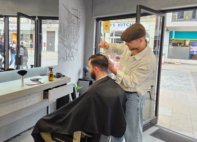 Barber styling client's hair at Anchor Lab, a trendy salon in London, England, GB.