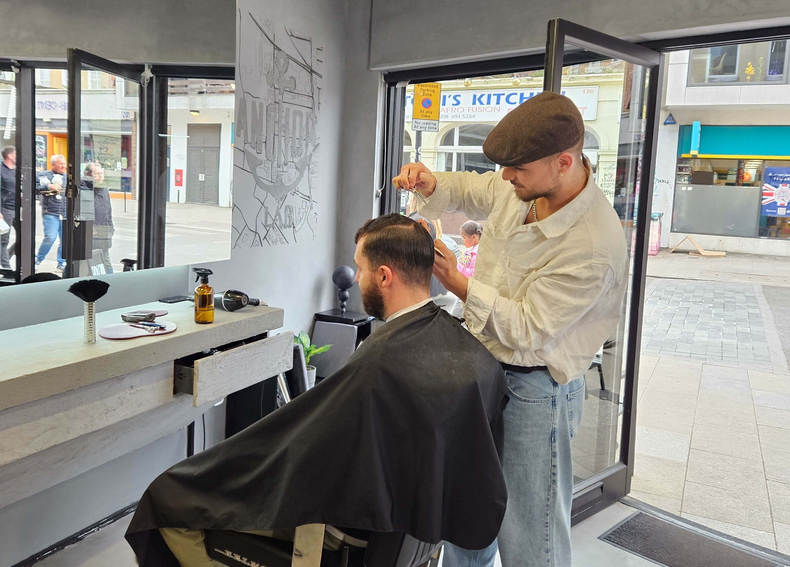 Barber styling client's hair at Anchor Lab, a trendy salon in London, England, GB.