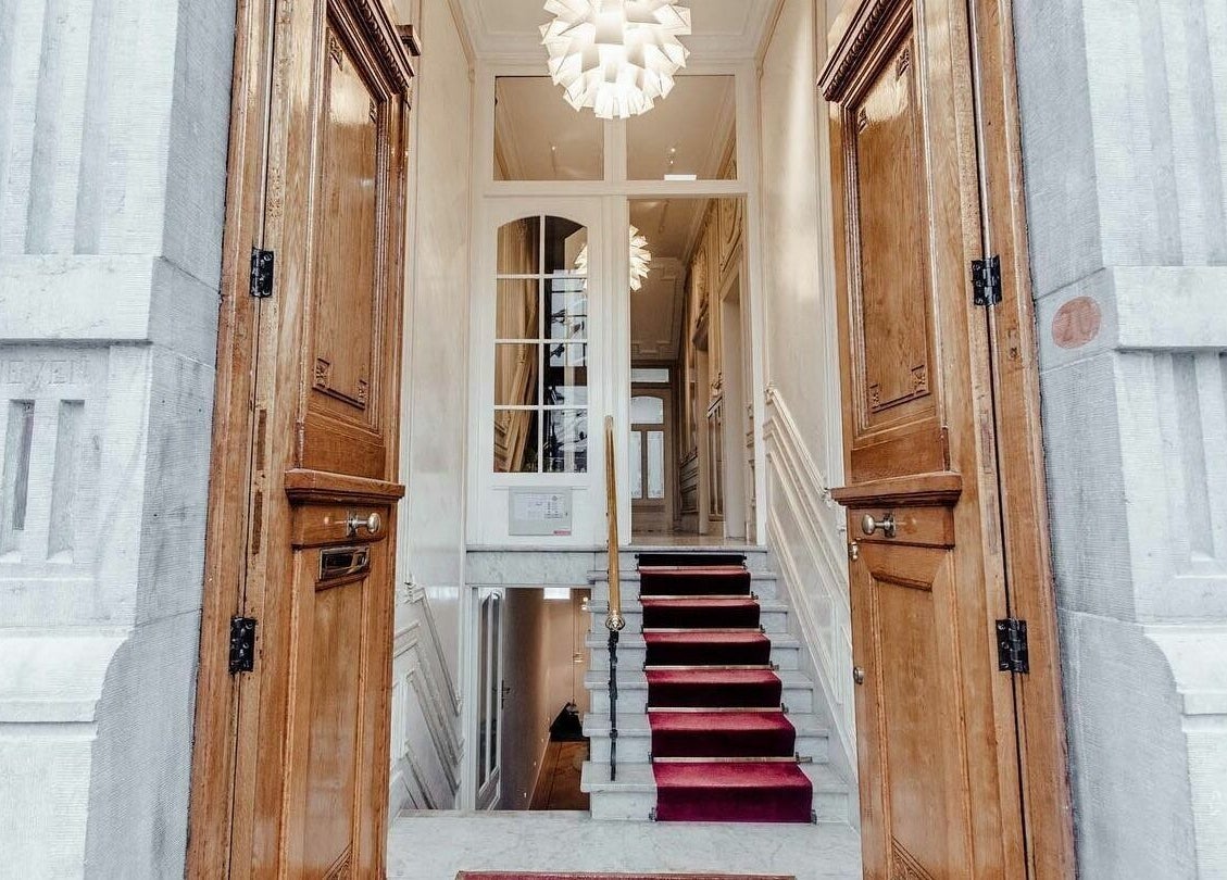 Elegant entrance of Sanctum Spa showcasing wooden doors and red carpet in Maastricht, Limburg, NL.