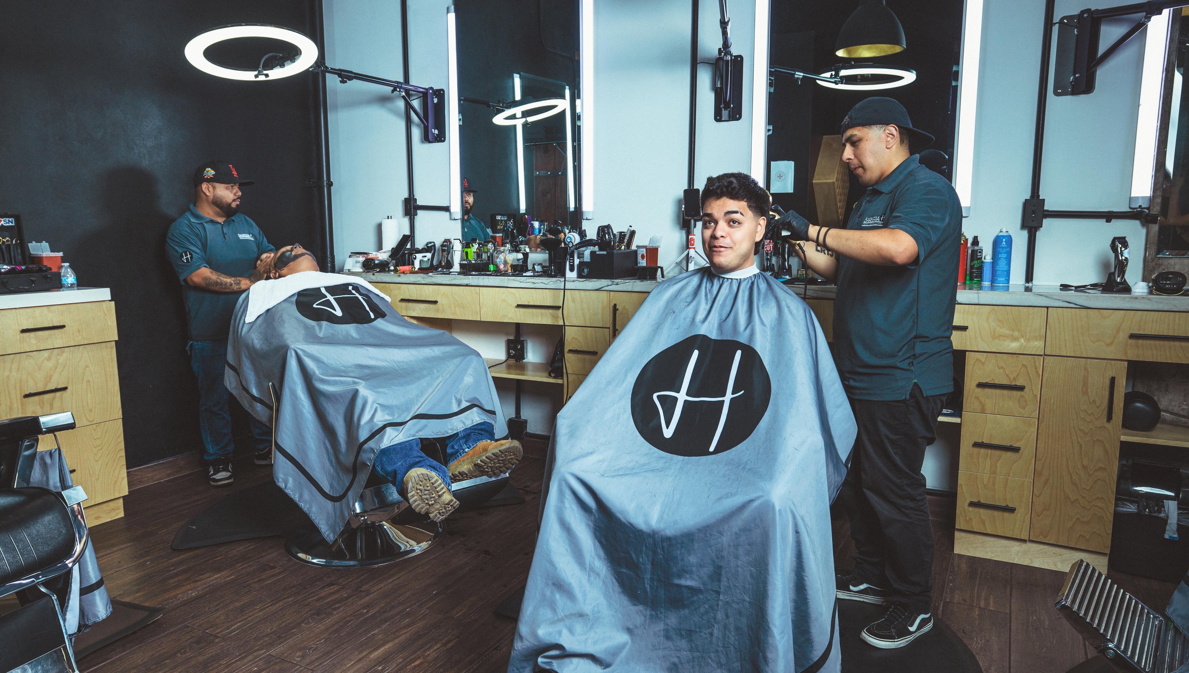Inside Barbería H in Tijuana, Baja California, MX, with customers getting haircuts in a modern setting.