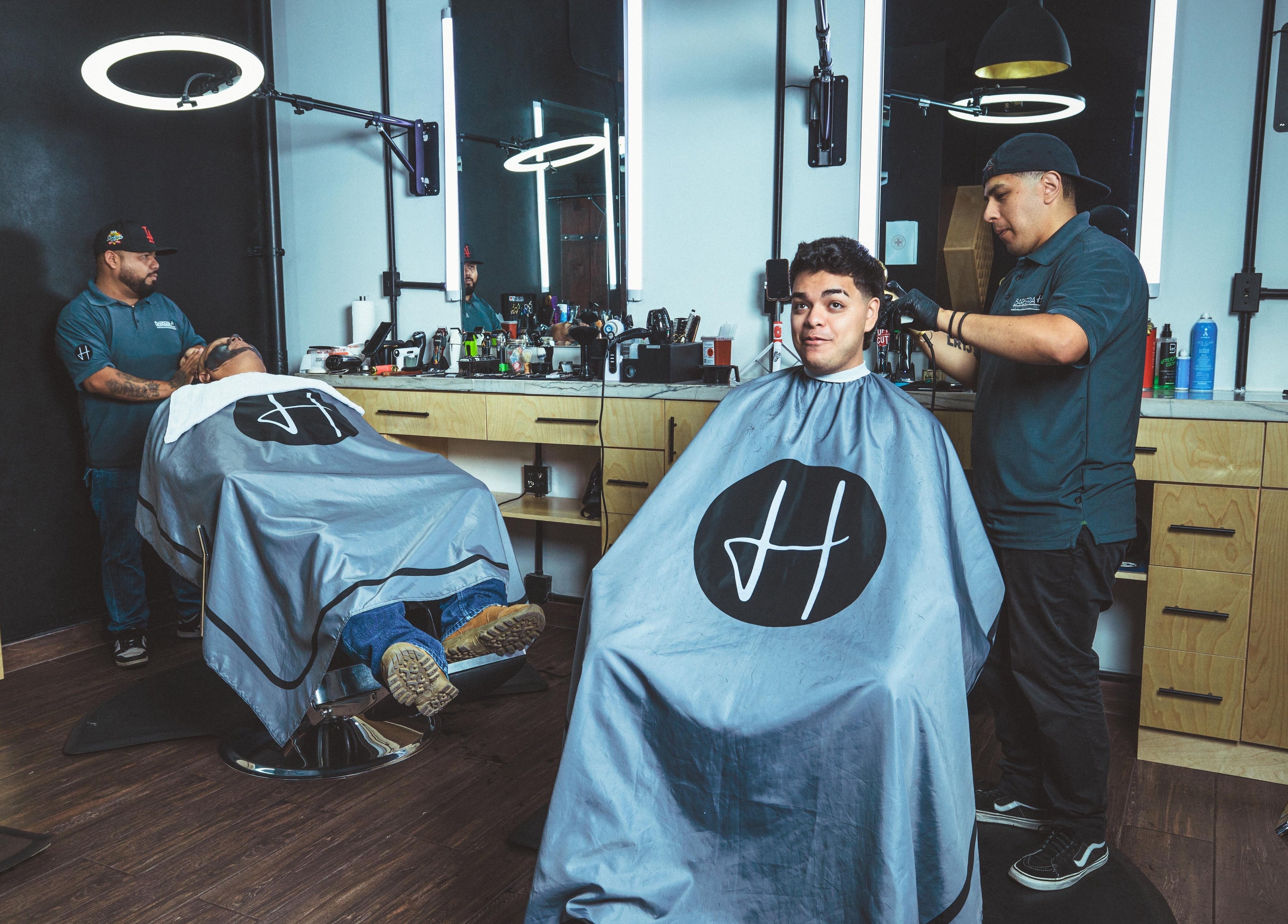 Inside Barbería H in Tijuana, Baja California, MX, with customers getting haircuts in a modern setting.