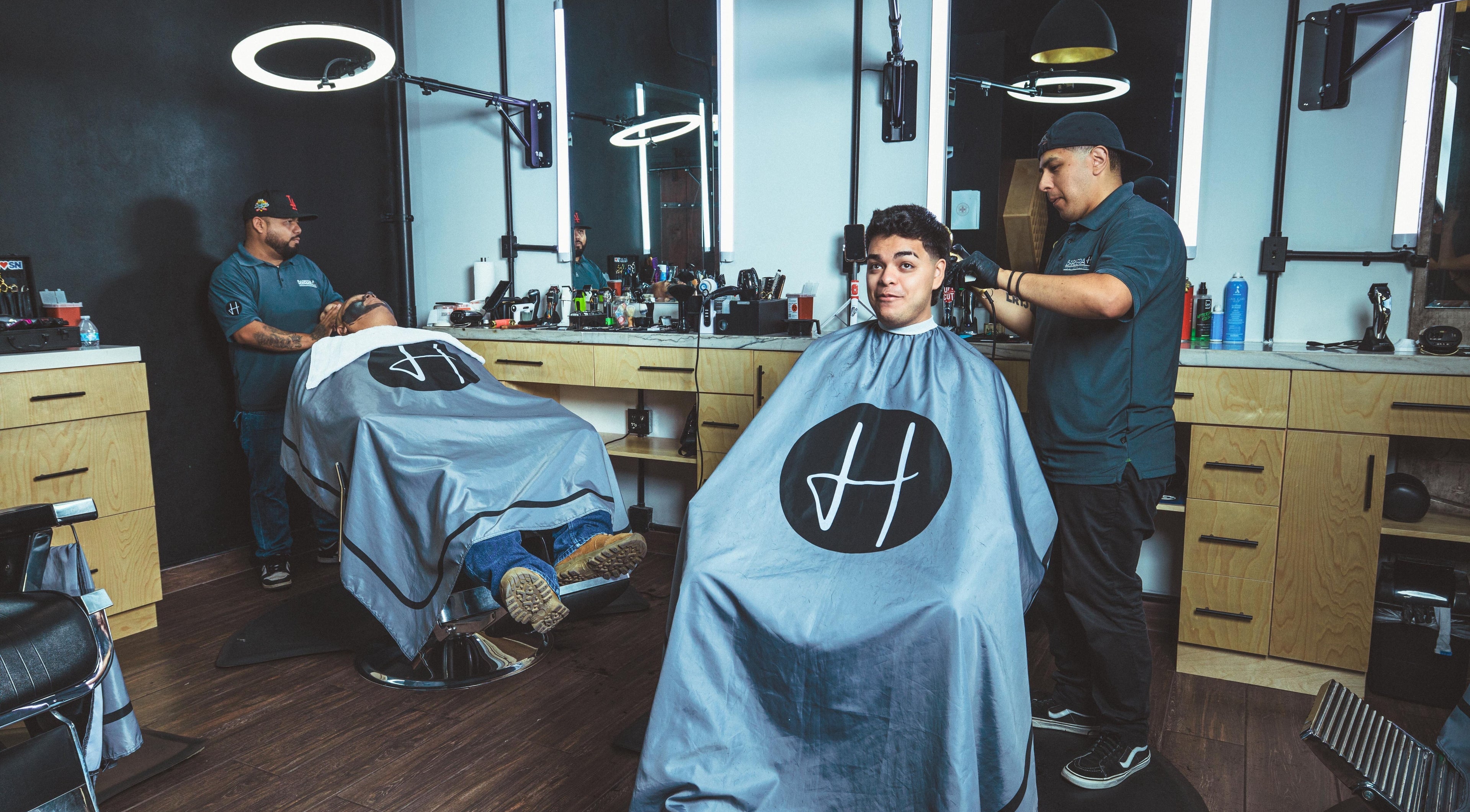 Inside Barbería H in Tijuana, Baja California, MX, with customers getting haircuts in a modern setting.