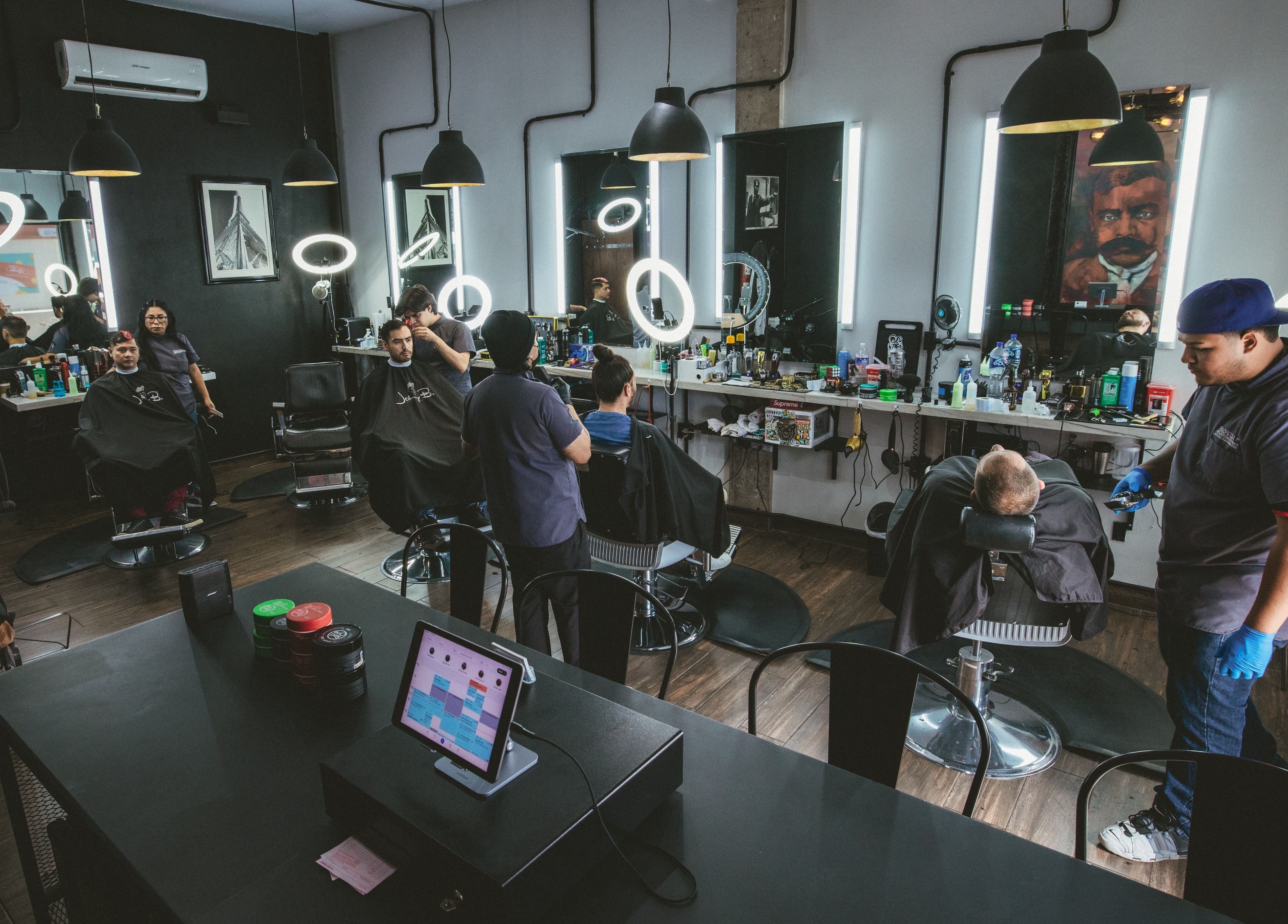 Modern barber shop interior at Barbería H, Tijuana, Baja California, MX with clients and barbers at work.
