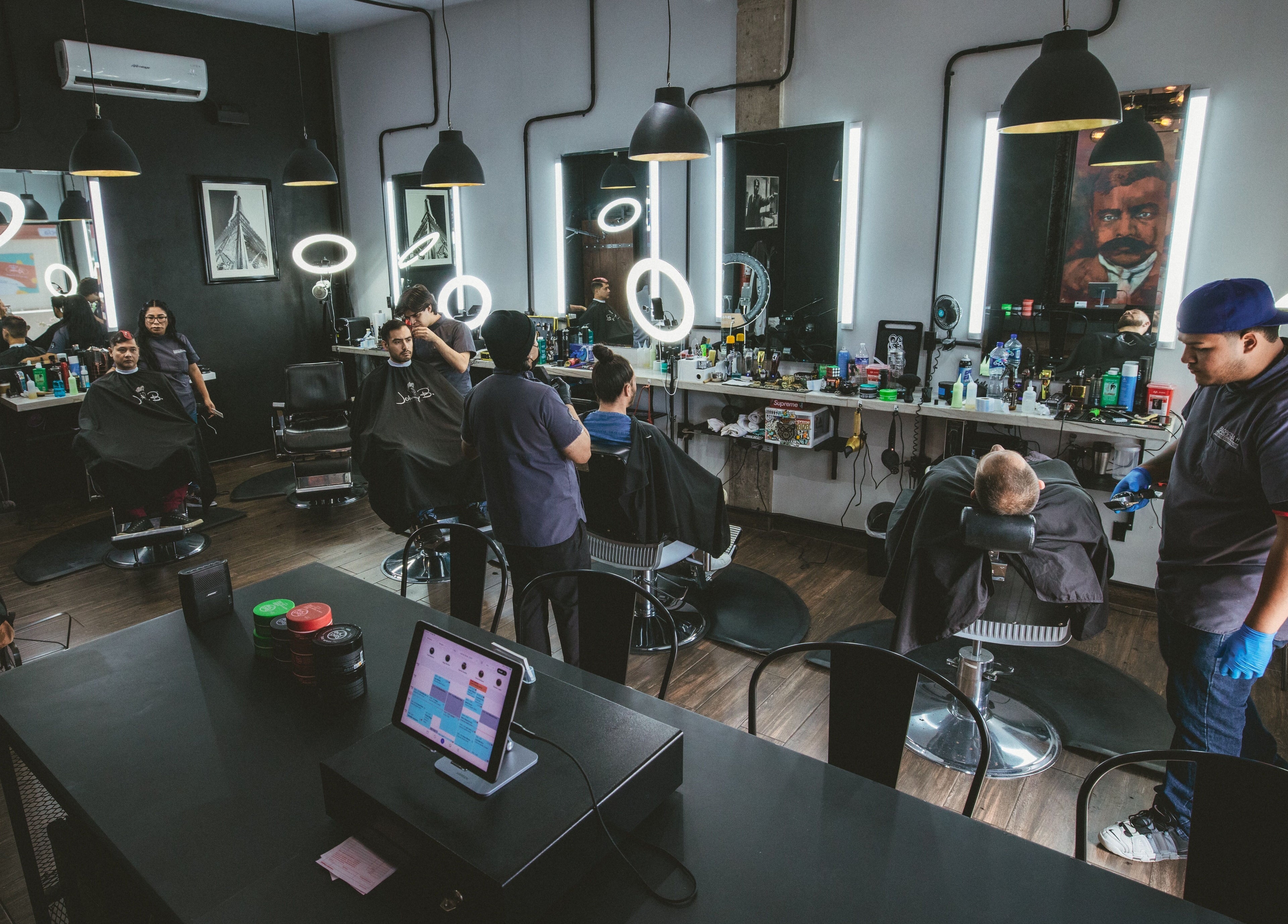 Modern barber shop interior at Barbería H, Tijuana, Baja California, MX with clients and barbers at work.