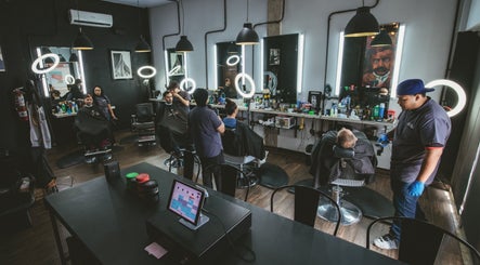 Modern barber shop interior at Barbería H, Tijuana, Baja California, MX with clients and barbers at work.