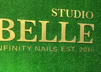 Infinity Nails signage on green wall in Windhoek, Khomas Region, NA. Stylish gold lettering enhances venue's charm.