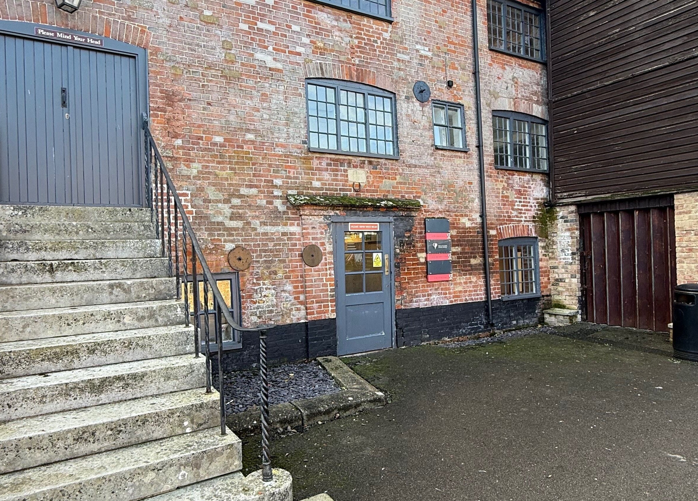 Rustic building entrance of M Aesthetics - Wilton in Wilton, England, GB, showcasing stairs and brick facade.