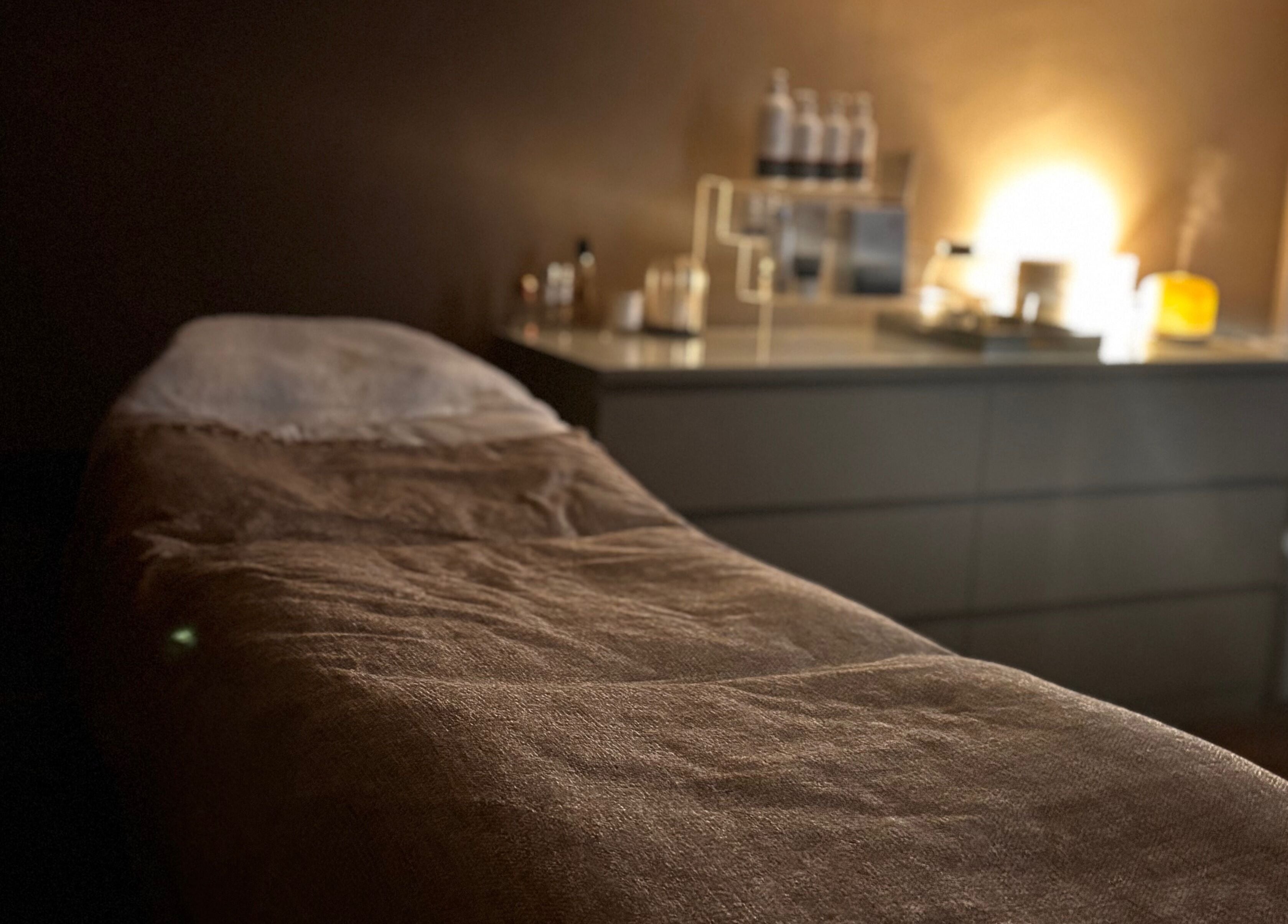 Cozy spa treatment room at Urban Spa, Morpeth, England, GB with ambient lighting and a massage table.