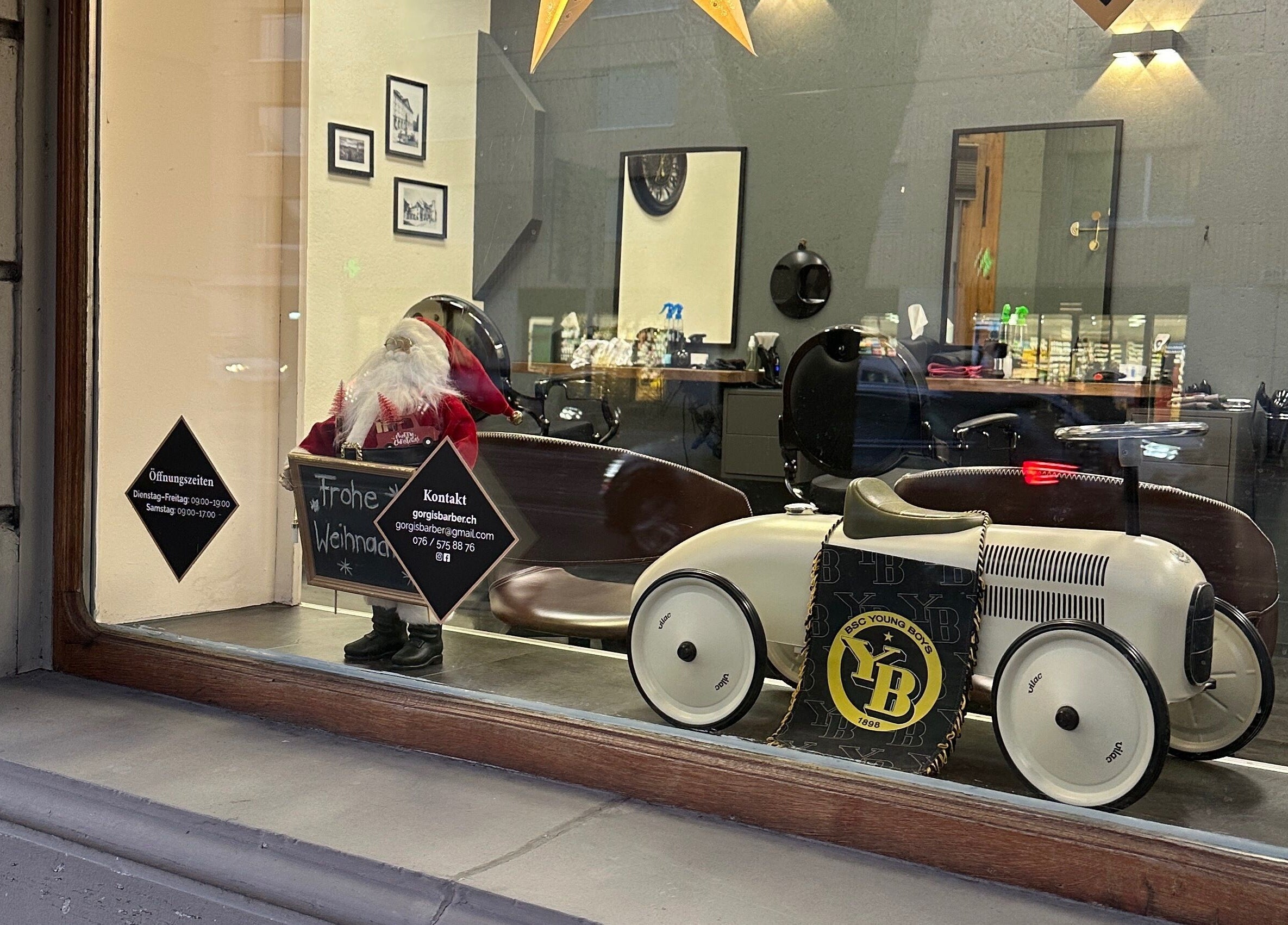 Weihnachtlich dekoriertes Fenster von Gorgis Barber Bern, Bern, CH mit Spielzeugauto und Weihnachtsmann.