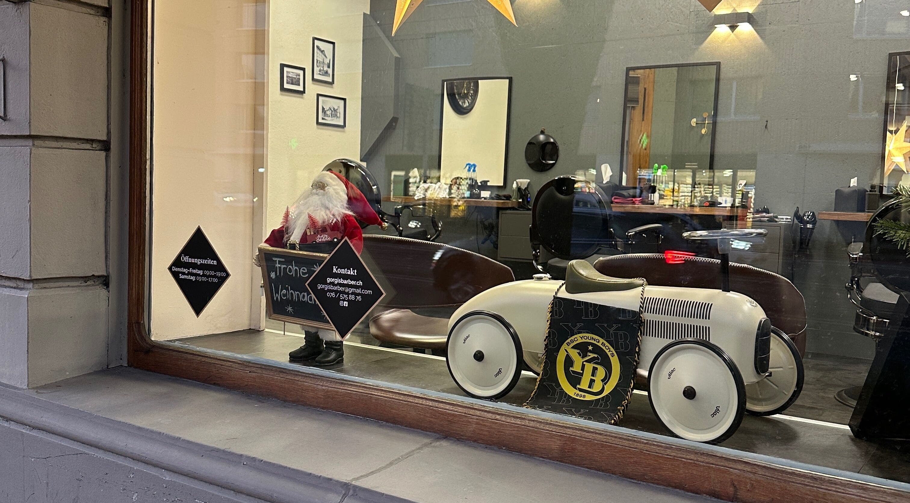 Weihnachtlich dekoriertes Fenster von Gorgis Barber Bern, Bern, CH mit Spielzeugauto und Weihnachtsmann.