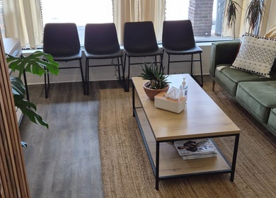 Relaxing waiting area at Revel Studio in London, Ontario, CA, featuring modern chairs and a stylish coffee table.