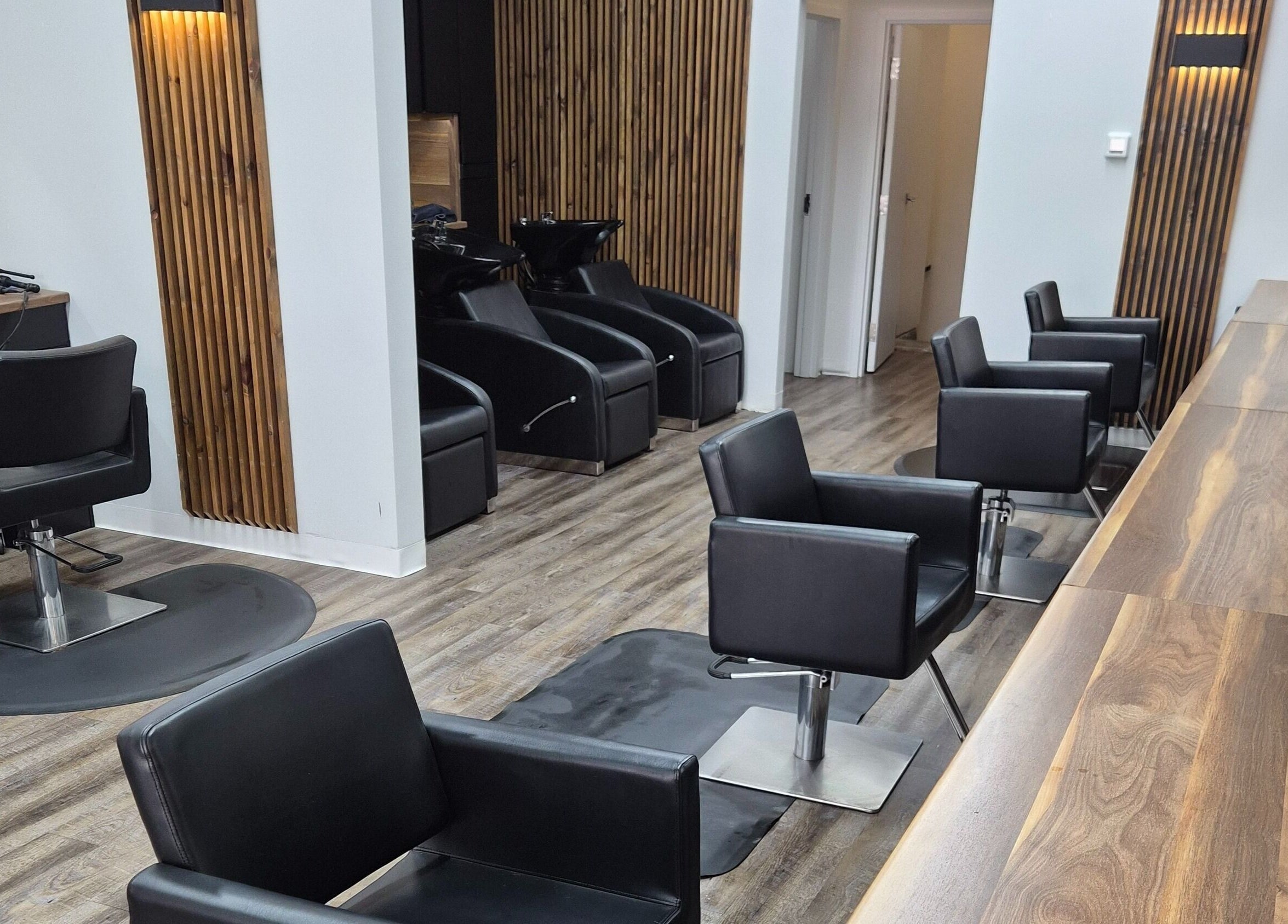 Modern salon setup at Revel Studio, London, Ontario, CA with stylish black chairs and wooden accents.