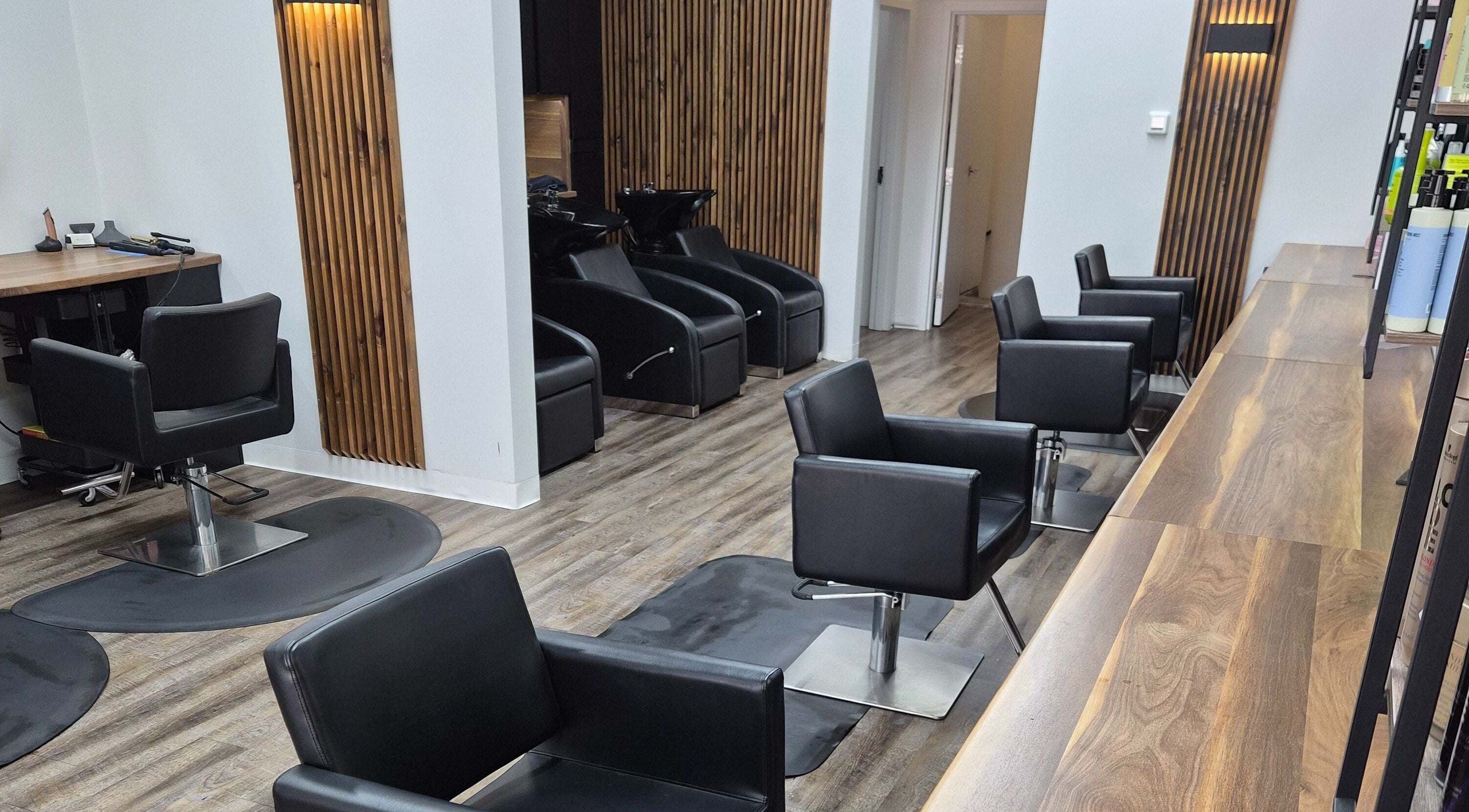 Modern salon setup at Revel Studio, London, Ontario, CA with stylish black chairs and wooden accents.