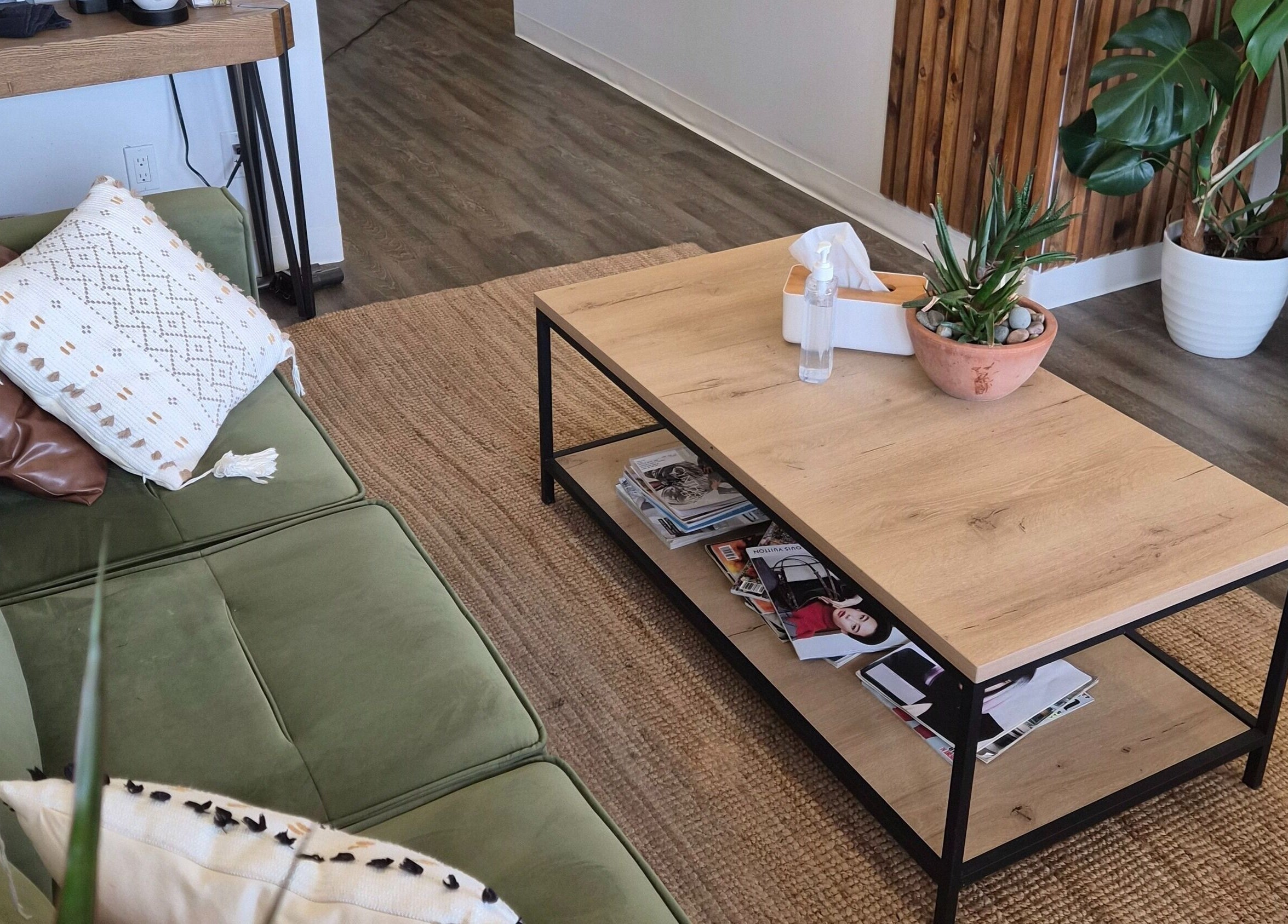 Cozy lounge area at Revel Studio in London, Ontario, CA, featuring a green sofa and wooden coffee table.