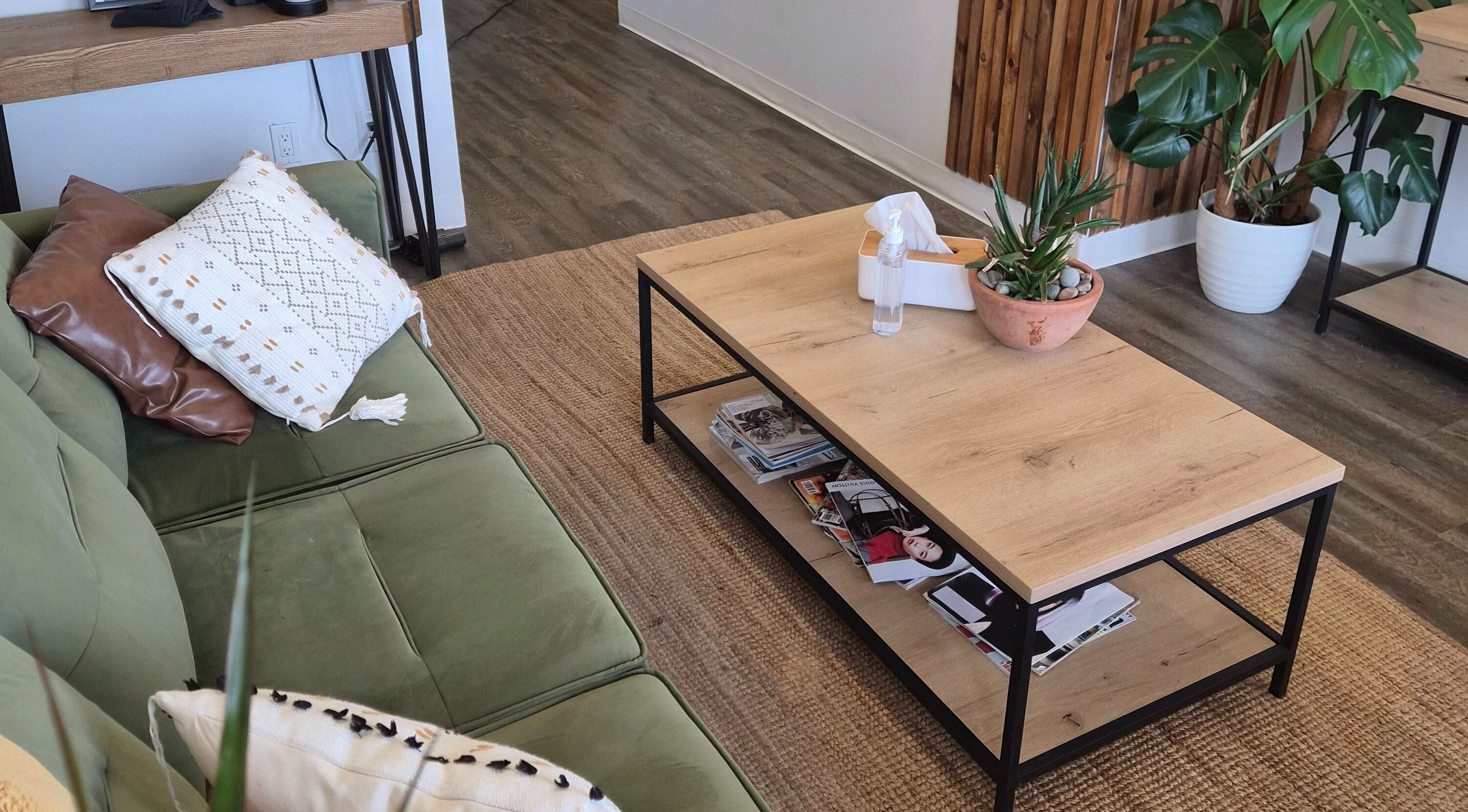Cozy lounge area at Revel Studio in London, Ontario, CA, featuring a green sofa and wooden coffee table.