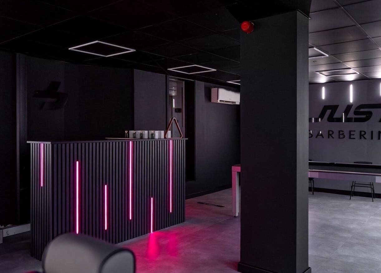 Chic interior of Just Barbering, Isle Of Man, Onchan, IM with sleek dark decor and vibrant lighting.