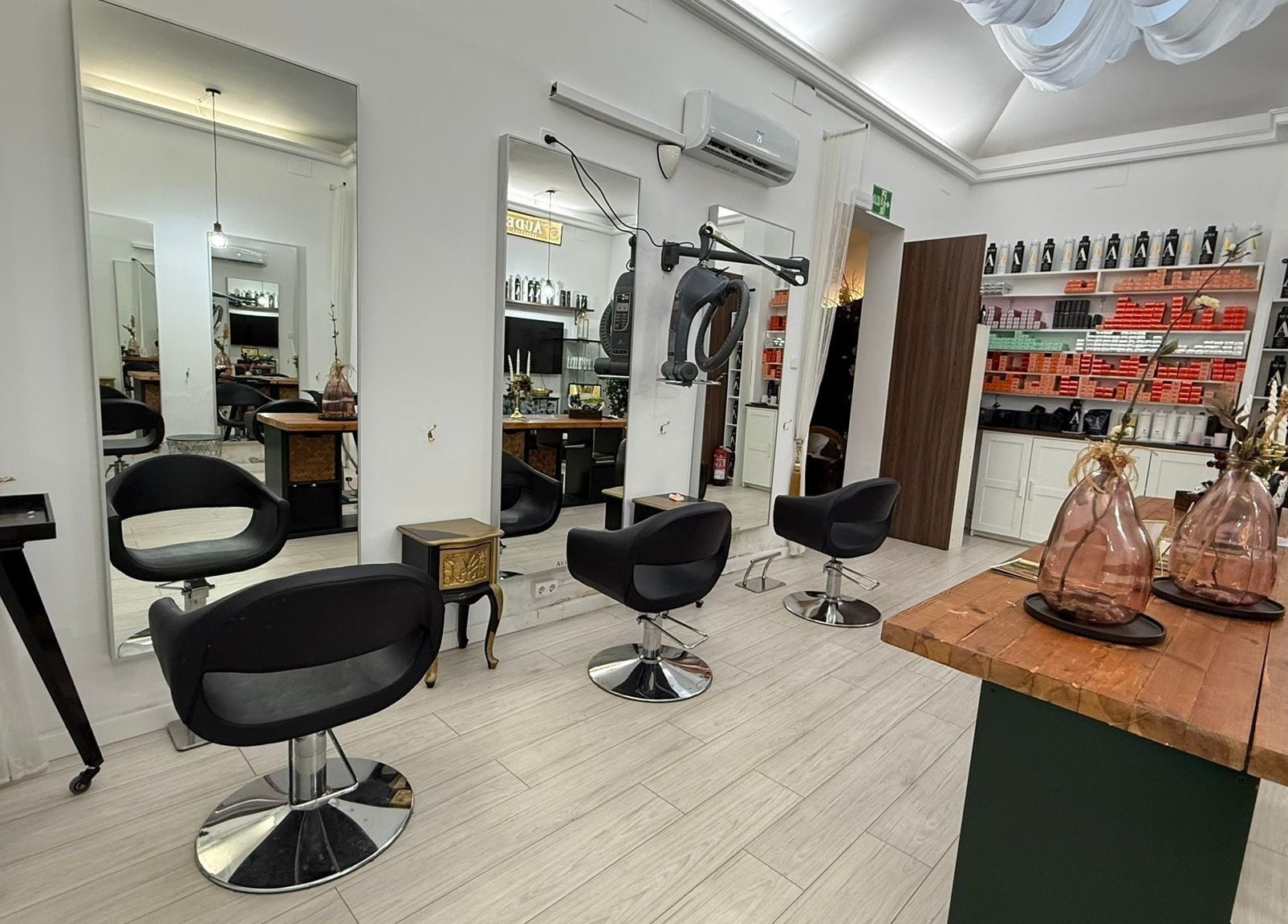 Interior moderno de Aude Perruqueria en Barcelona, Catalunya, ES, con sillas negras y espejos grandes.