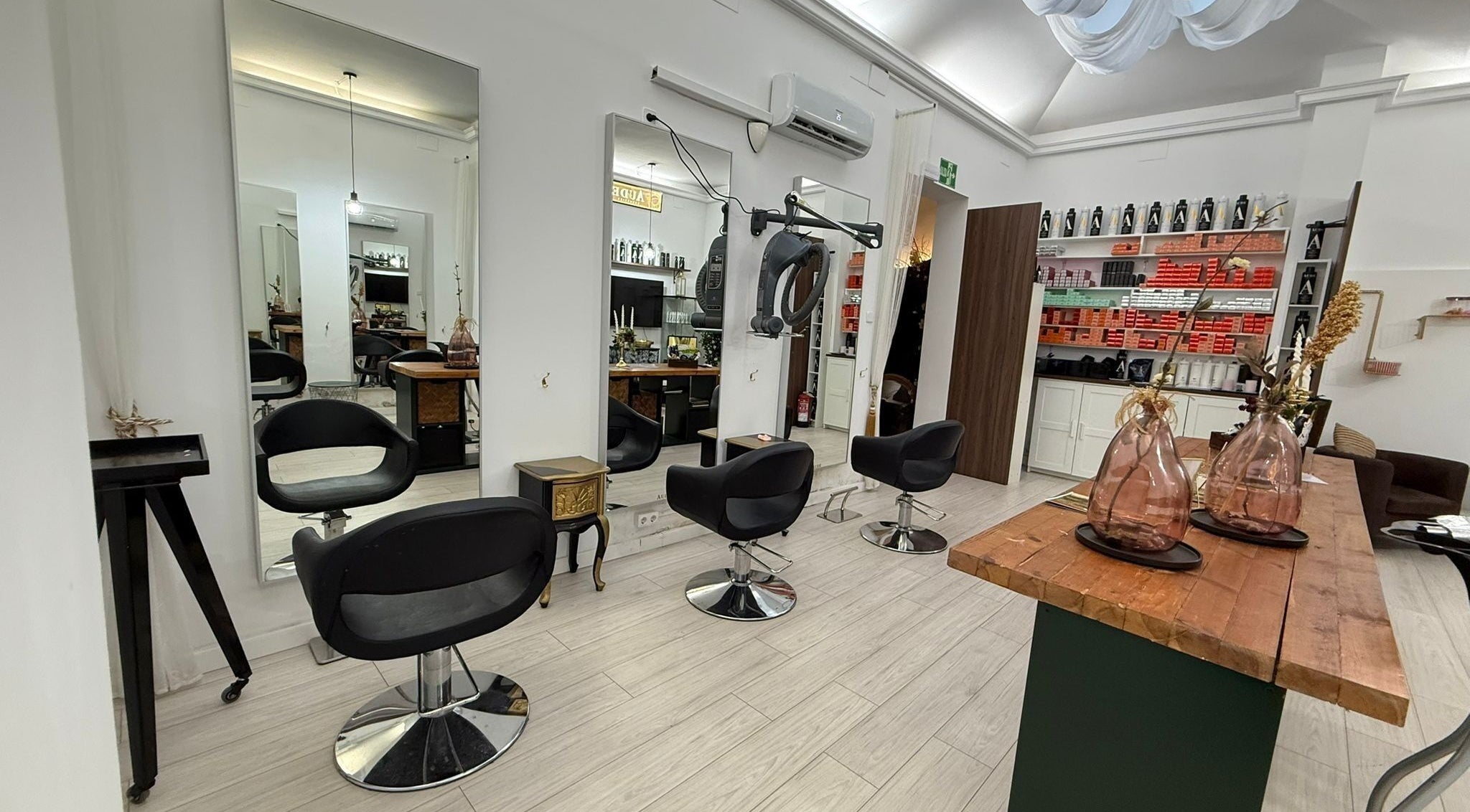 Interior moderno de Aude Perruqueria en Barcelona, Catalunya, ES, con sillas negras y espejos grandes.