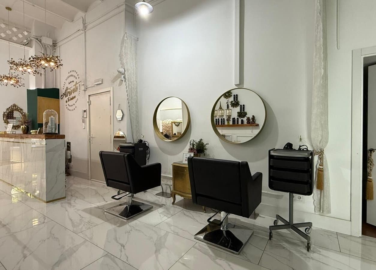 Interior elegante de Aude Perruqueria, espejos dorados y sillas negras en Barcelona, Catalunya, ES.