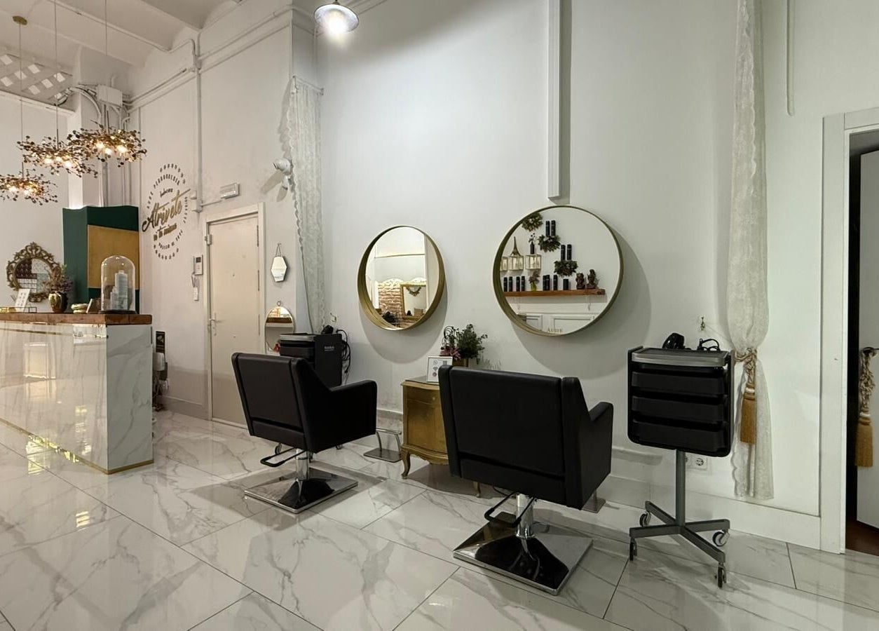 Interior elegante de Aude Perruqueria, espejos dorados y sillas negras en Barcelona, Catalunya, ES.