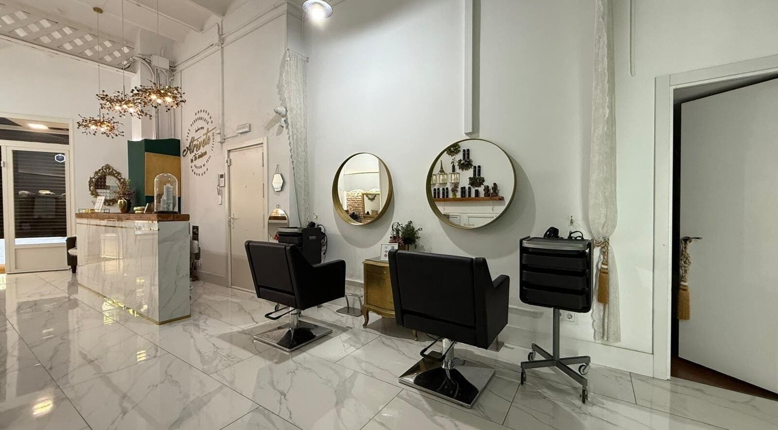 Interior elegante de Aude Perruqueria, espejos dorados y sillas negras en Barcelona, Catalunya, ES.