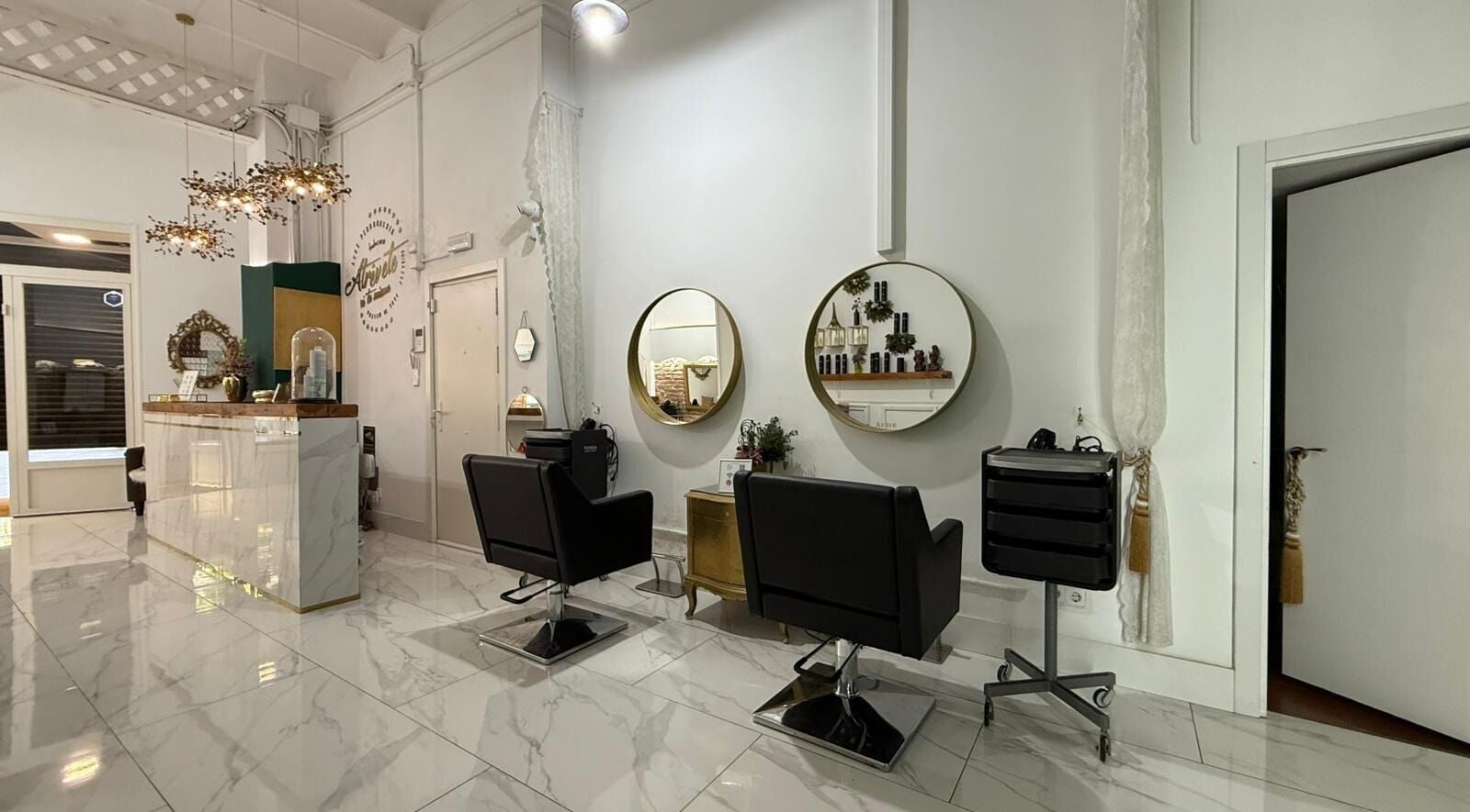 Interior elegante de Aude Perruqueria, espejos dorados y sillas negras en Barcelona, Catalunya, ES.