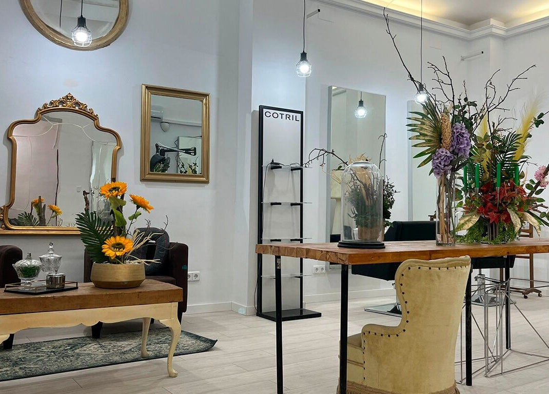 Interiores elegantes de Aude Perruqueria en Barcelona, Catalunya, ES con decoración floral y espejos dorados.