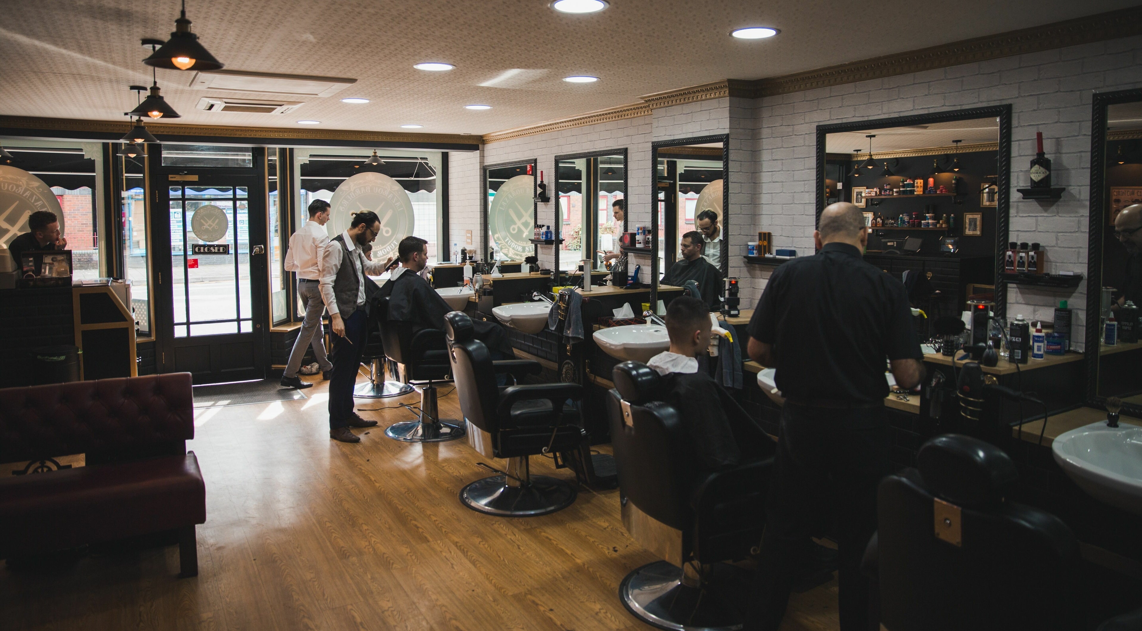 Interior of Lazarou Barbers Tudor Stret in Cardiff, Wales, GB, showcasing stylish barbers and clients.