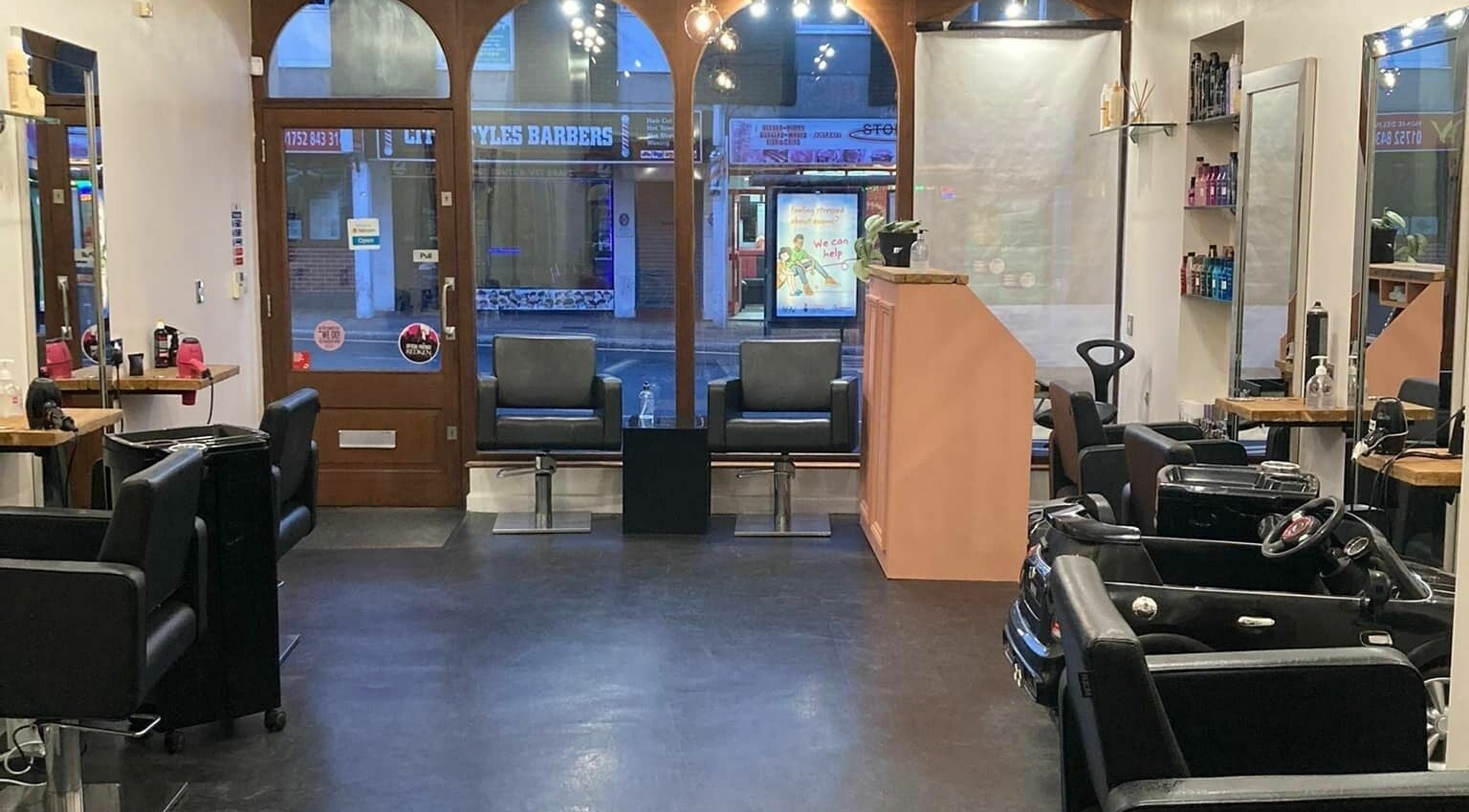 Spacious interior of Cutabove Hair Salon in Saltash, England, GB, featuring modern styling chairs and large windows.