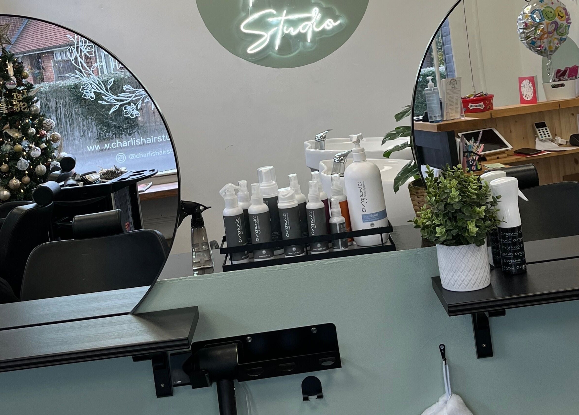 Inside Charli's Hair Studio, Beccles, England, GB. Elegant mirrors reflect salon's festive decor and organic products.