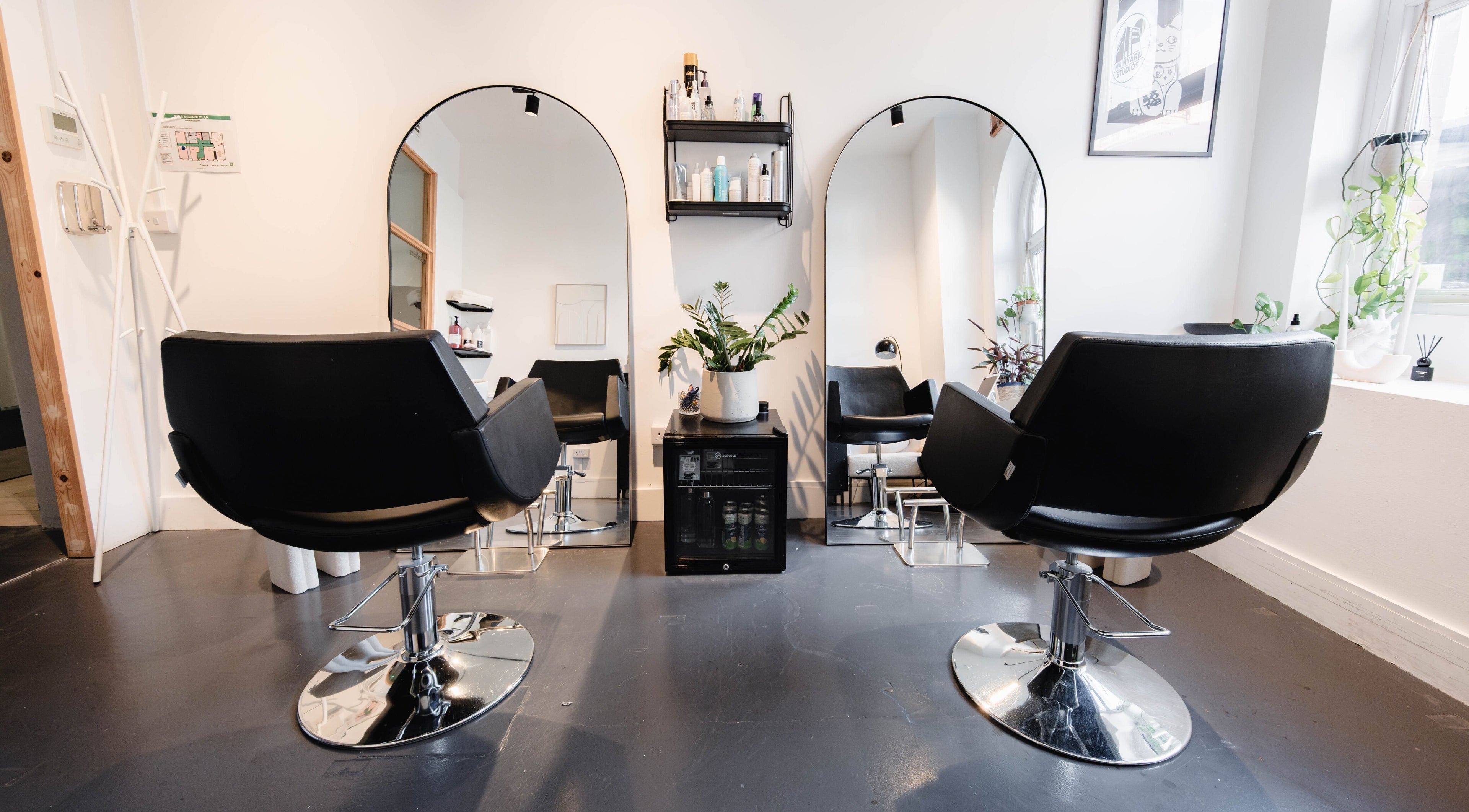 Chic interior of Haircvlt Hackney with black salon chairs and mirrors, London, England, GB.