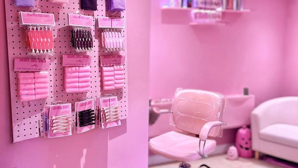 Inside Lucilles Locks, Long Eaton, England. A pink salon setup with hair accessories and a stylish chair.