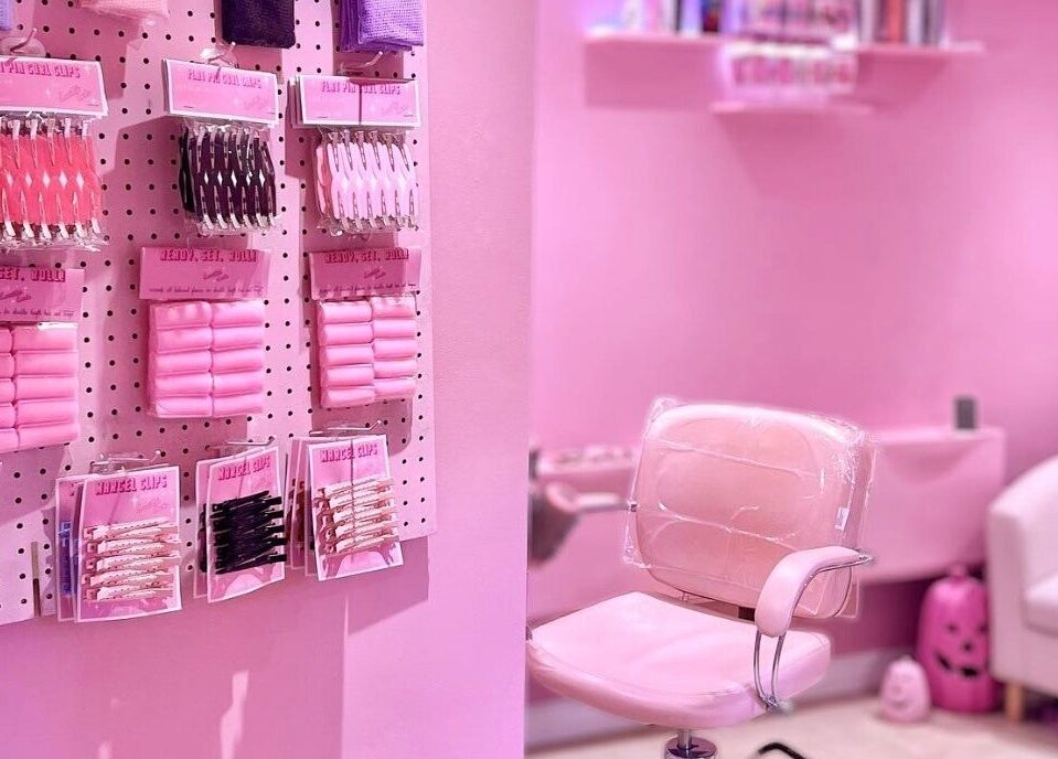 Inside Lucilles Locks, Long Eaton, England. A pink salon setup with hair accessories and a stylish chair.