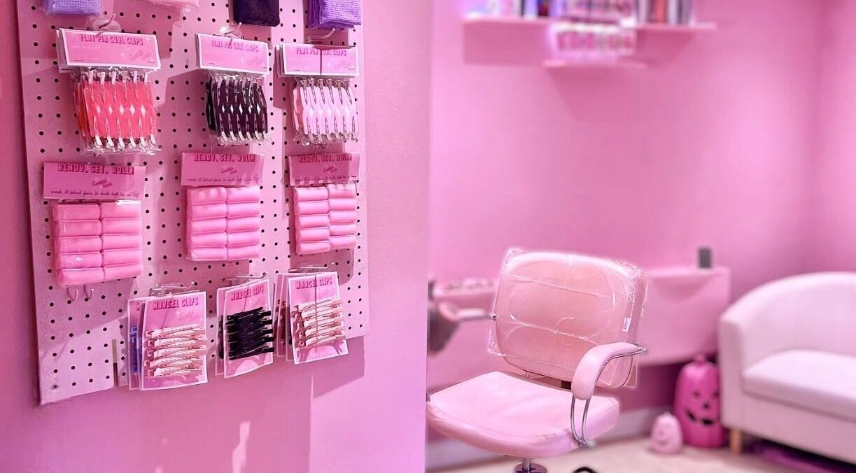 Inside Lucilles Locks, Long Eaton, England. A pink salon setup with hair accessories and a stylish chair.