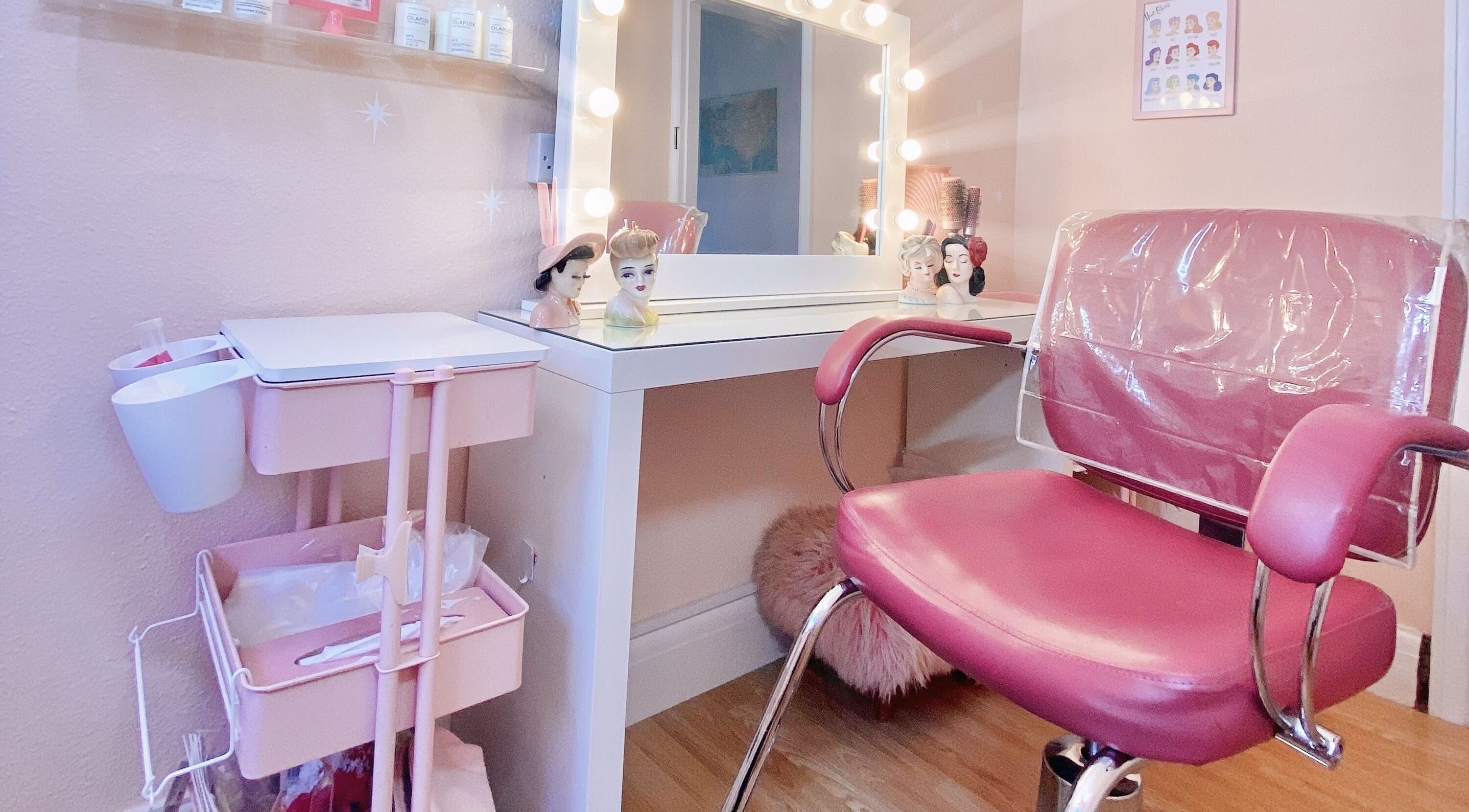 Chic salon station at Lucilles Locks, Long Eaton, England, GB, featuring a pink chair and vanity mirrors.