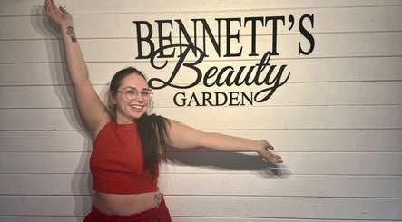 A smiling visitor at Bennett’s Beauty Garden, Warrington, England, GB, in front of the venue sign.