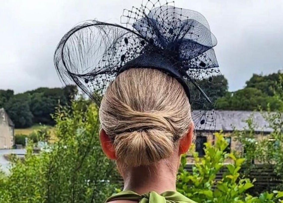 Elegant updo with black fascinator at Cabello, Birstall, England, GB, showcasing scenic greenery.
