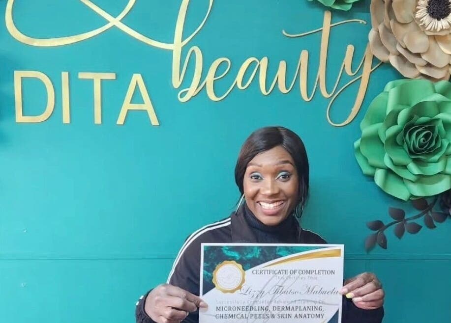 Smiling woman holding a certificate at Me Time in Edenvale, Gauteng, ZA with decorative floral backdrop.