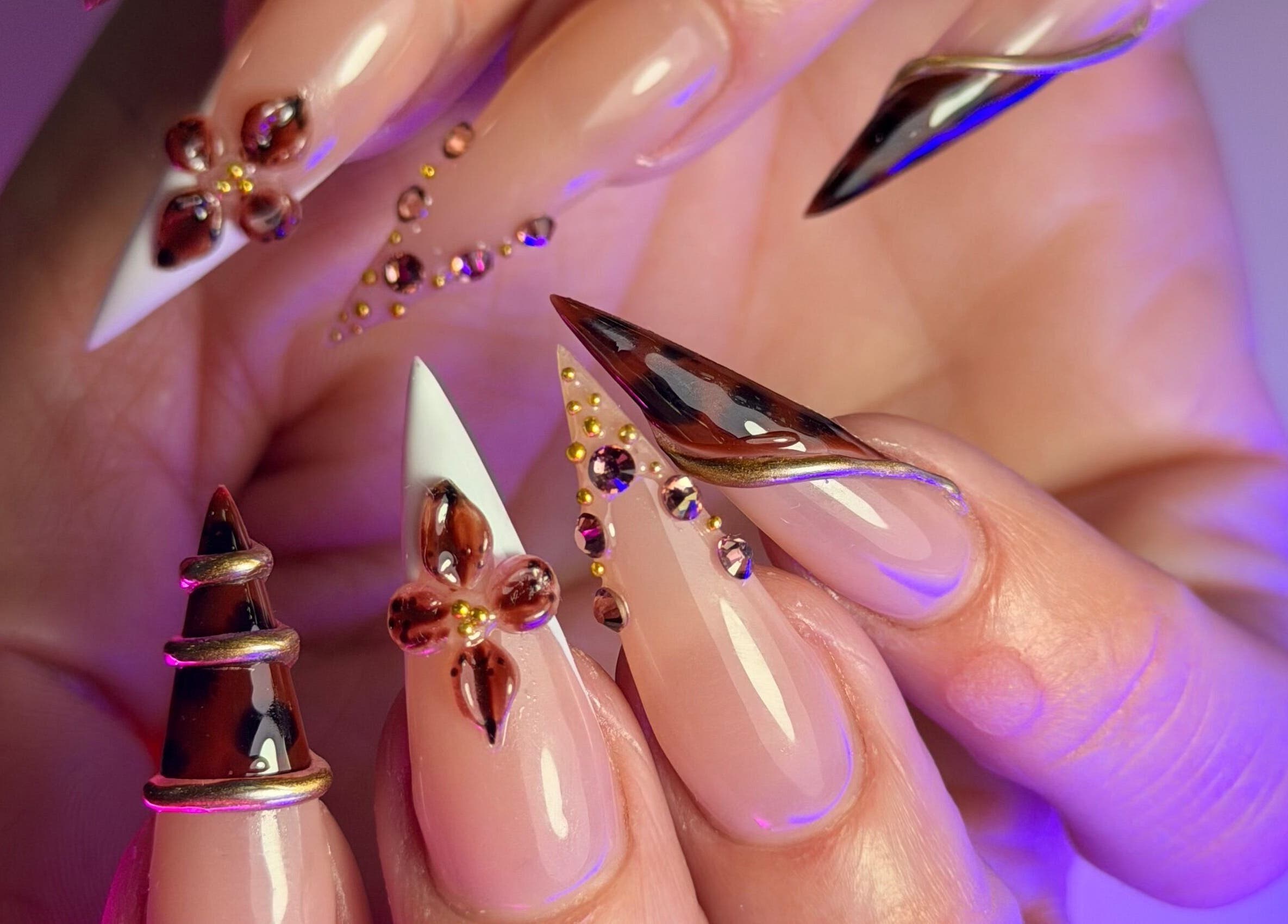 Intricate nail art at Get The Gloss, Hamilton, Scotland, GB features gems and metallic highlights.