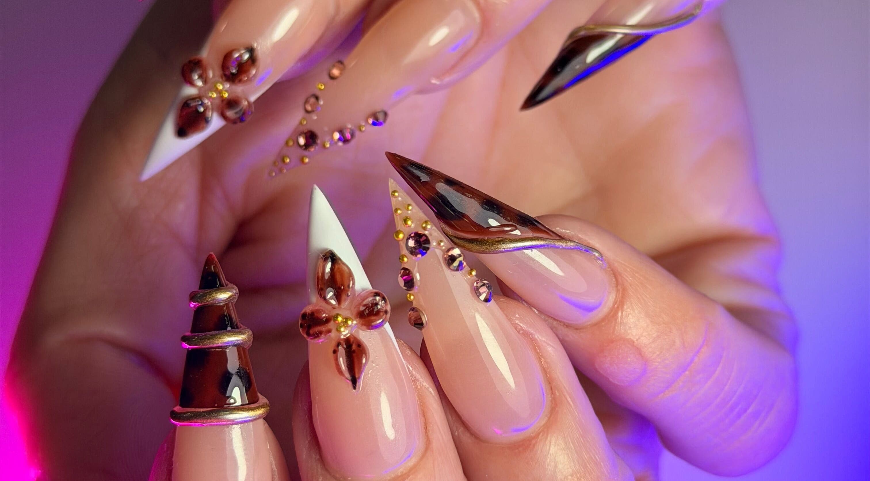 Intricate nail art at Get The Gloss, Hamilton, Scotland, GB features gems and metallic highlights.