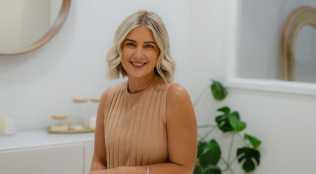 Smiling professional at Zovia Beauty, Griffith, Australian Capital Territory, AU, with elegant decor in background.