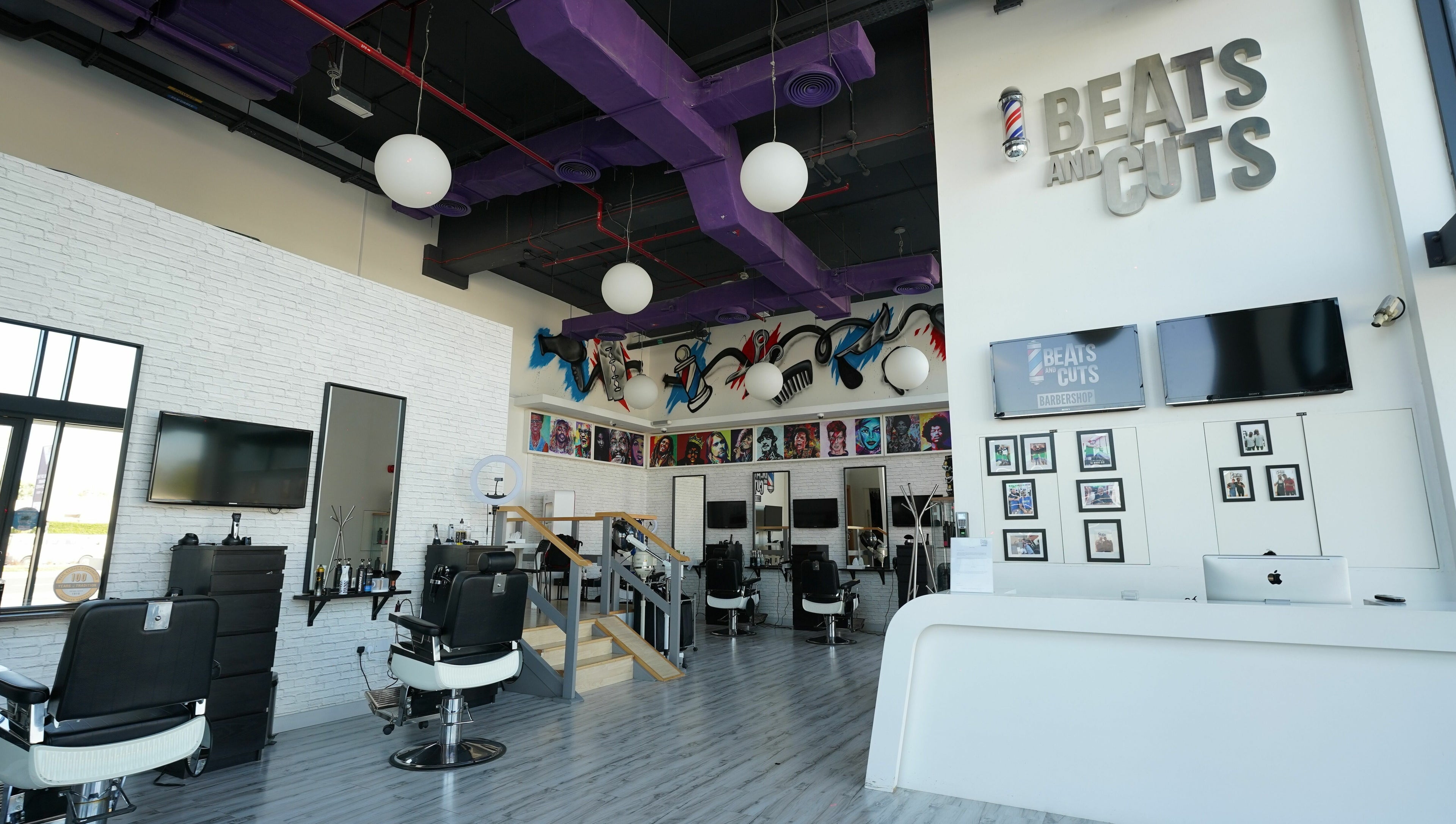 Stylish interior of Beats and Cuts in Dubai, AE. Modern design with sleek barber chairs and vibrant artwork.