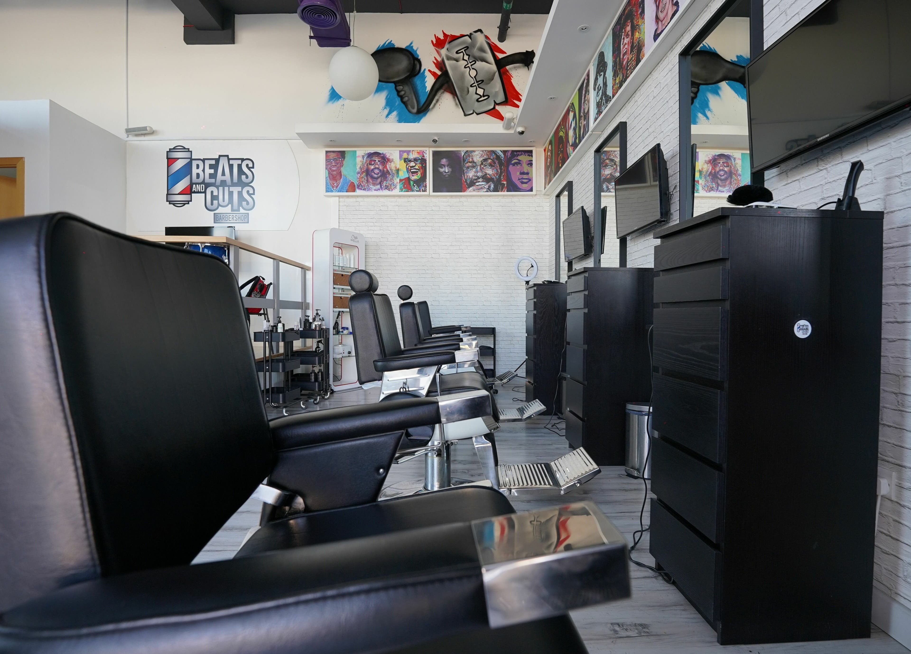 Modern interior of Beats and Cuts barbershop in Dubai, AE with stylish black chairs and vibrant wall art.