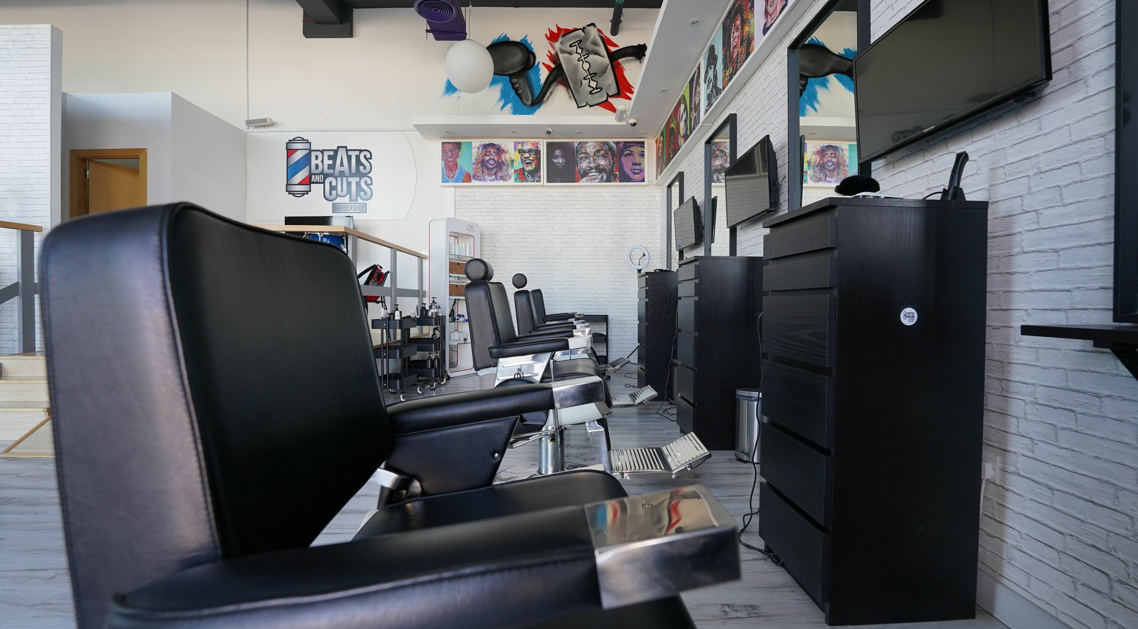 Modern interior of Beats and Cuts barbershop in Dubai, AE with stylish black chairs and vibrant wall art.