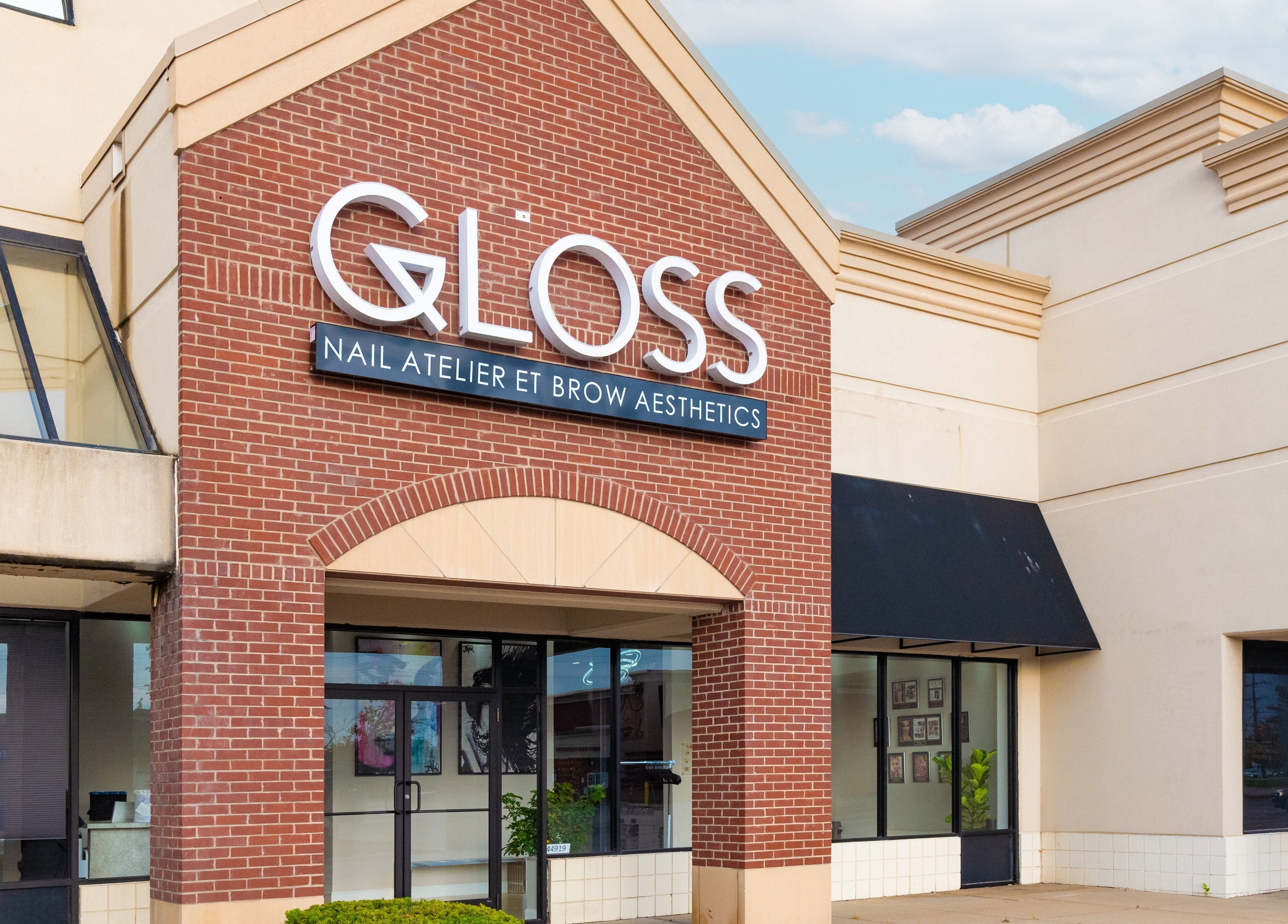Front entrance of Gloss Nail Atelier in Sterling Heights, Michigan, US, showcasing stylish brick facade.