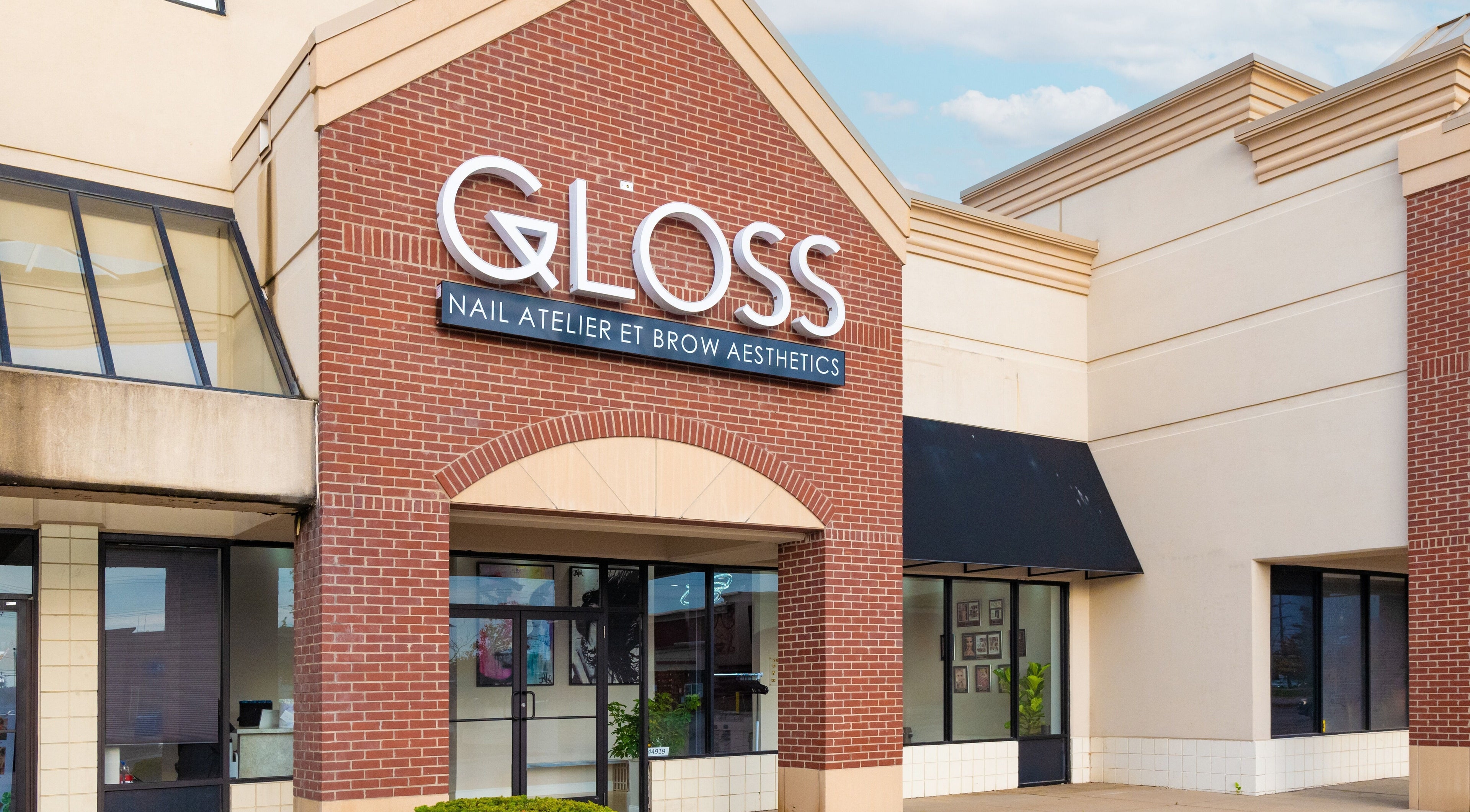 Front entrance of Gloss Nail Atelier in Sterling Heights, Michigan, US, showcasing stylish brick facade.